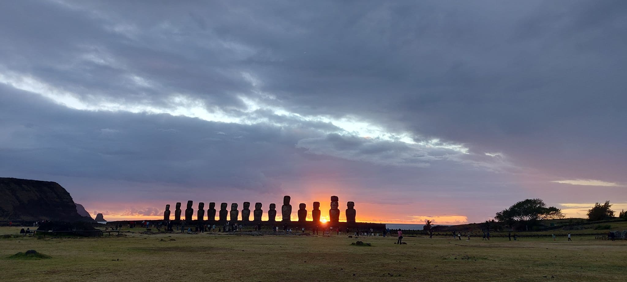 Ahu Tongariki Moai silhouetted at sunrise on Rapa Nui (Easter Island), Chile, with visitors on the grassy foreground.