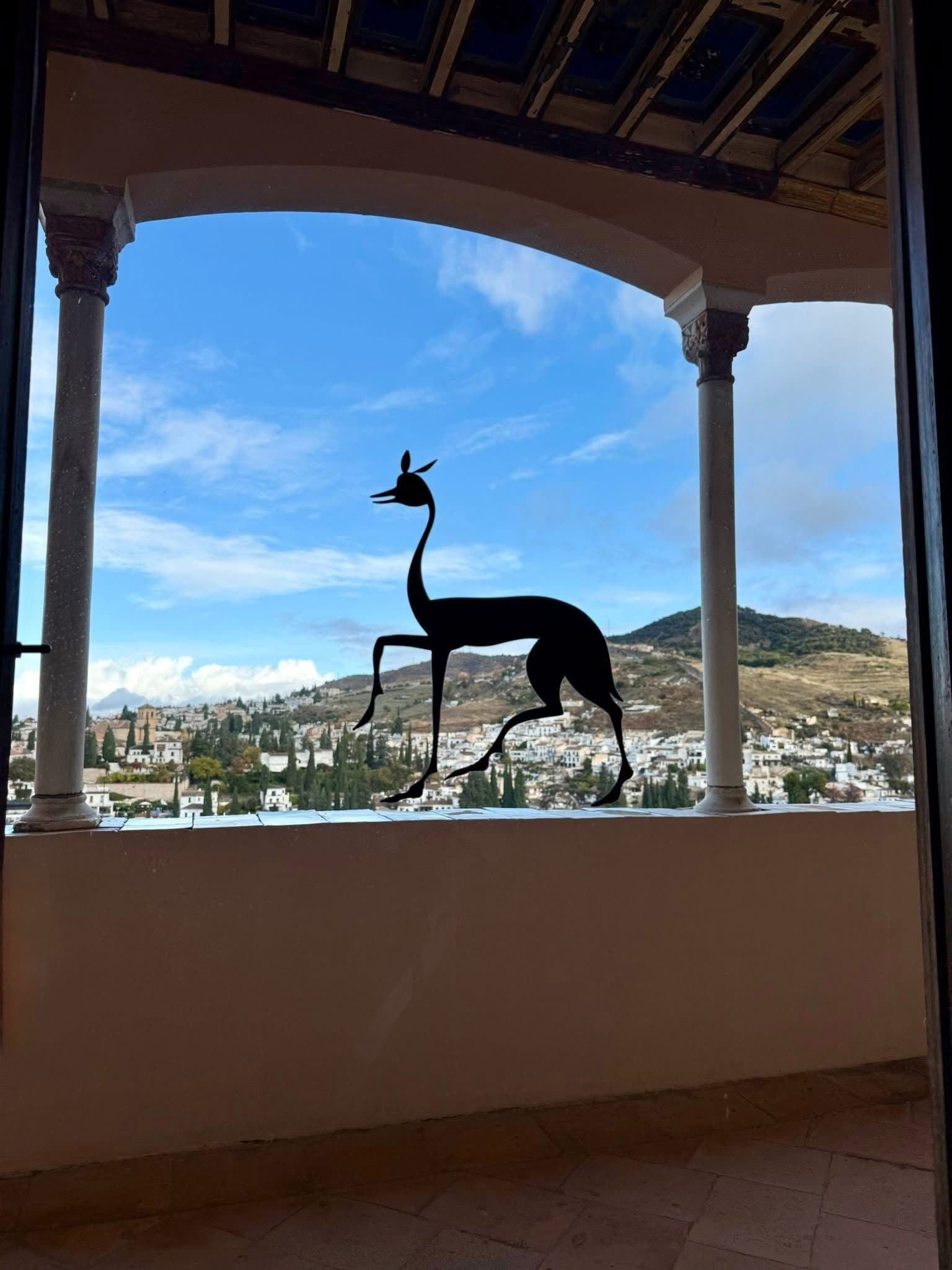 Decorative animal silhouette on a balcony window framing the Albayzín neighborhood in Granada, Spain.