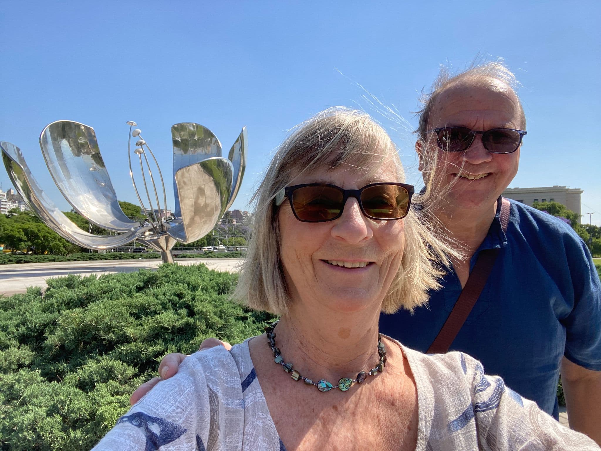 Floralis Genérica sculpture with two travelers taking a selfie in Plaza Naciones Unidas, Buenos Aires, Argentina.