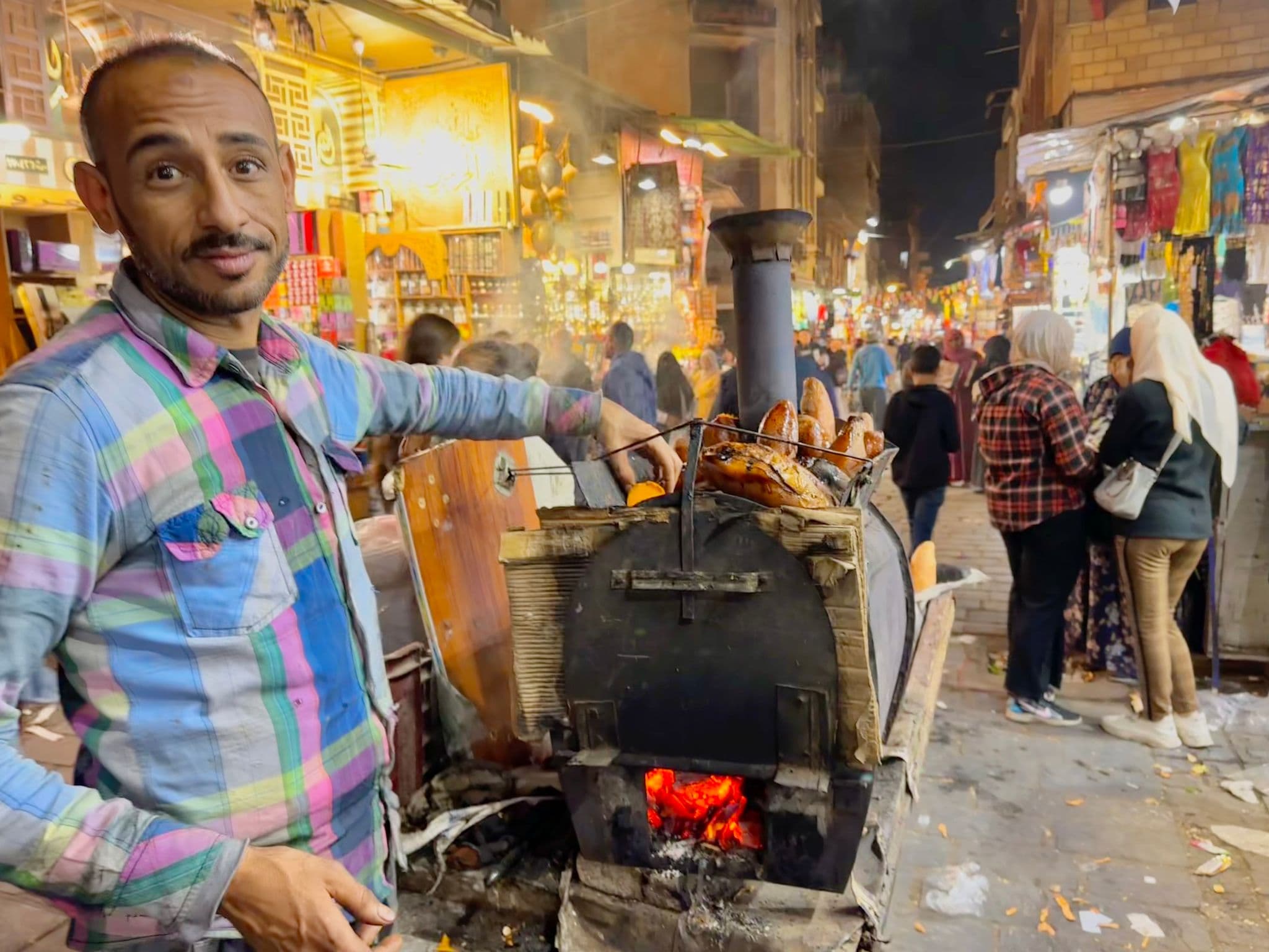 A street vendor grilling bread at a wood-fired oven in a crowded Khan el-Khalili market, Cairo, Egypt.