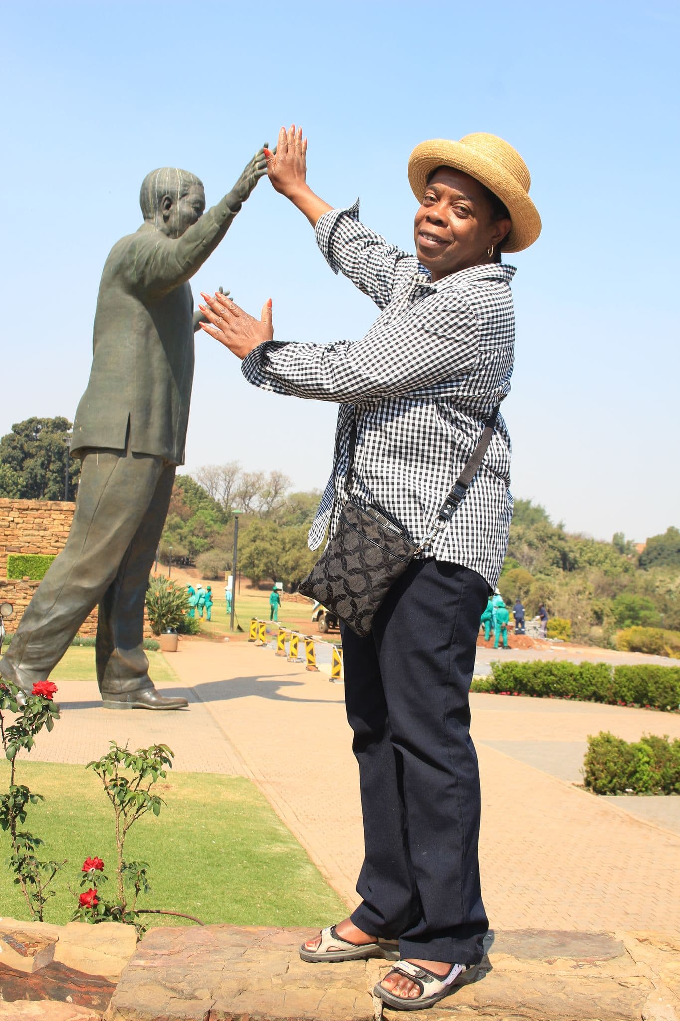 Nelson Mandela statue with a woman posing as if high-fiving it in a park in Johannesburg, South Africa.