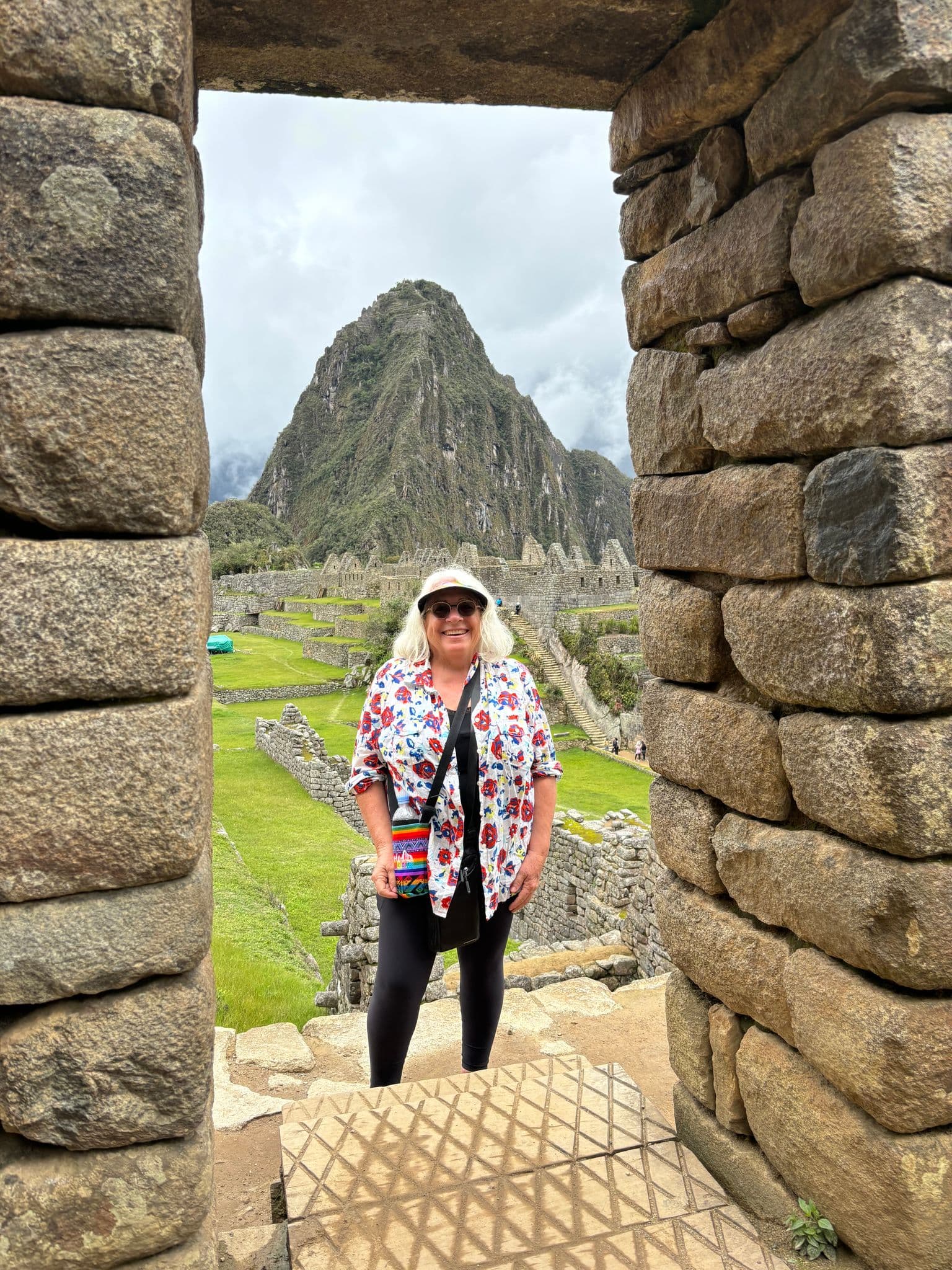 Machu Picchu doorway framing a woman standing in the ruins with Huayna Picchu behind, Cusco, Peru.