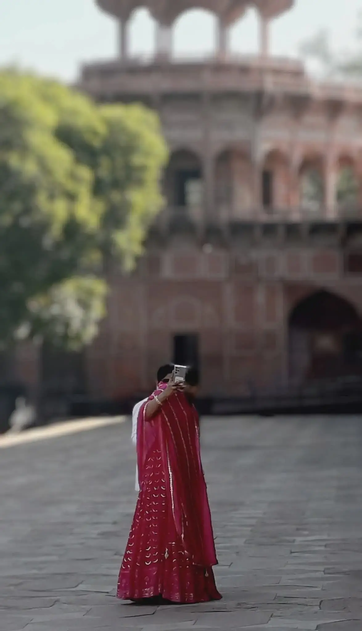 Fatehpur Sikri courtyard with a woman in a pink sari taking a photo, Uttar Pradesh, India.