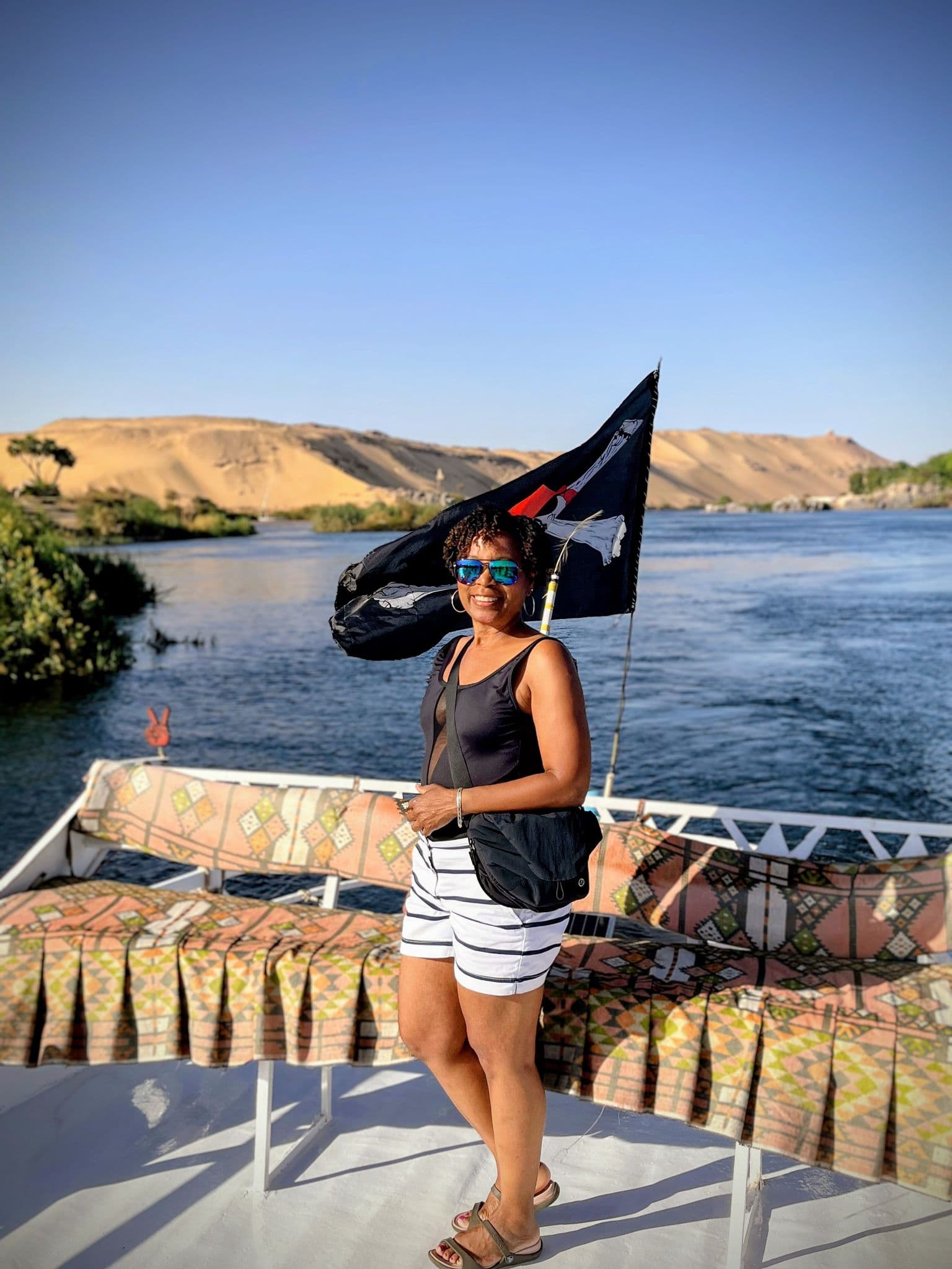 Nile River with a woman standing on a boat en route to a Nubian village in Egypt.