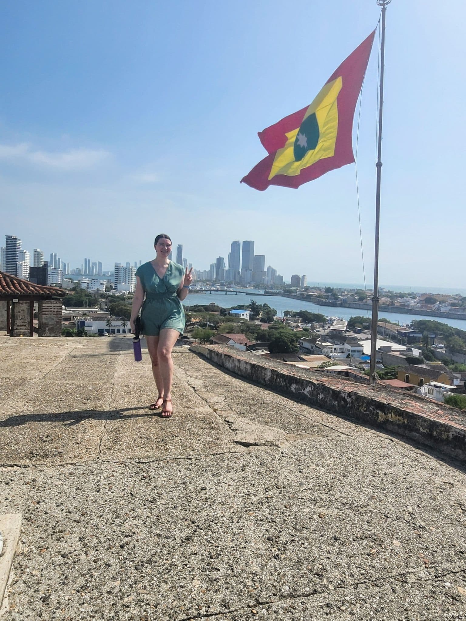 Traveler standing on the Castillo de San Felipe de Barajas ramparts with the Cartagena skyline and Bocagrande towers in the background, Colombia.