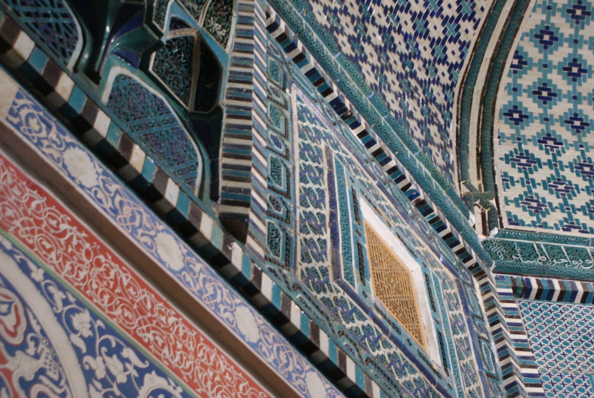 Ornate blue and turquoise mosaic tiles covering an arched interior wall, historic architecture in Uzbekistan.