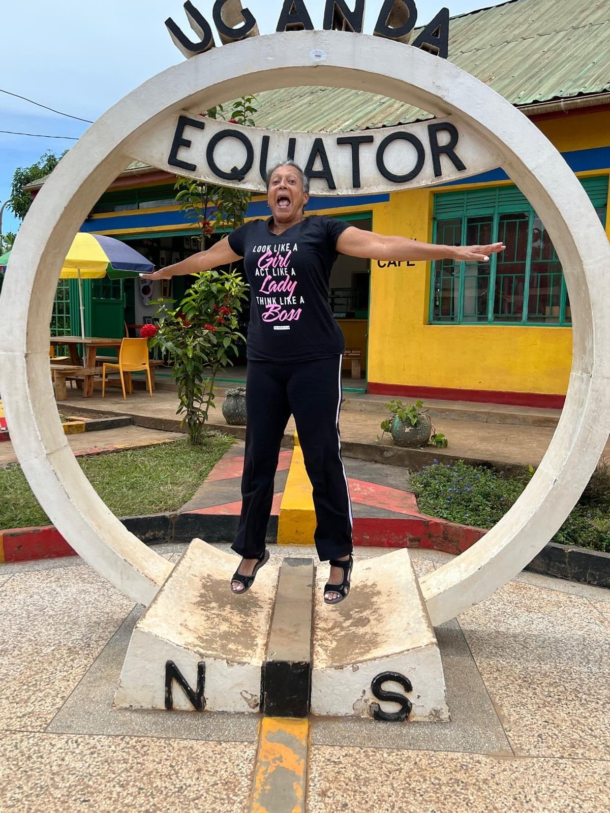 Equator monument ring with a traveler jumping through it at the Uganda Equator marker, Uganda.