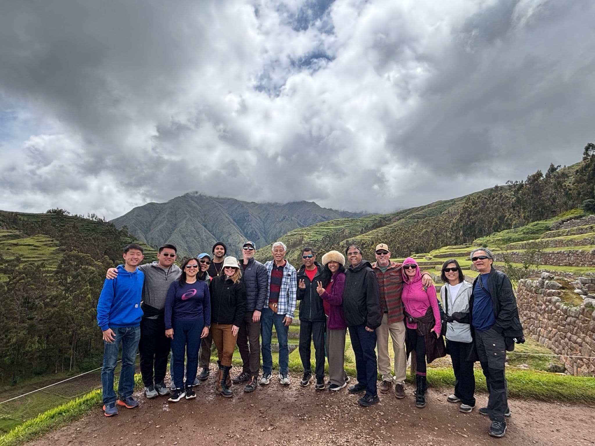 Group of travelers posing on terraced hillside with mountains in the Sacred Valley, Peru.