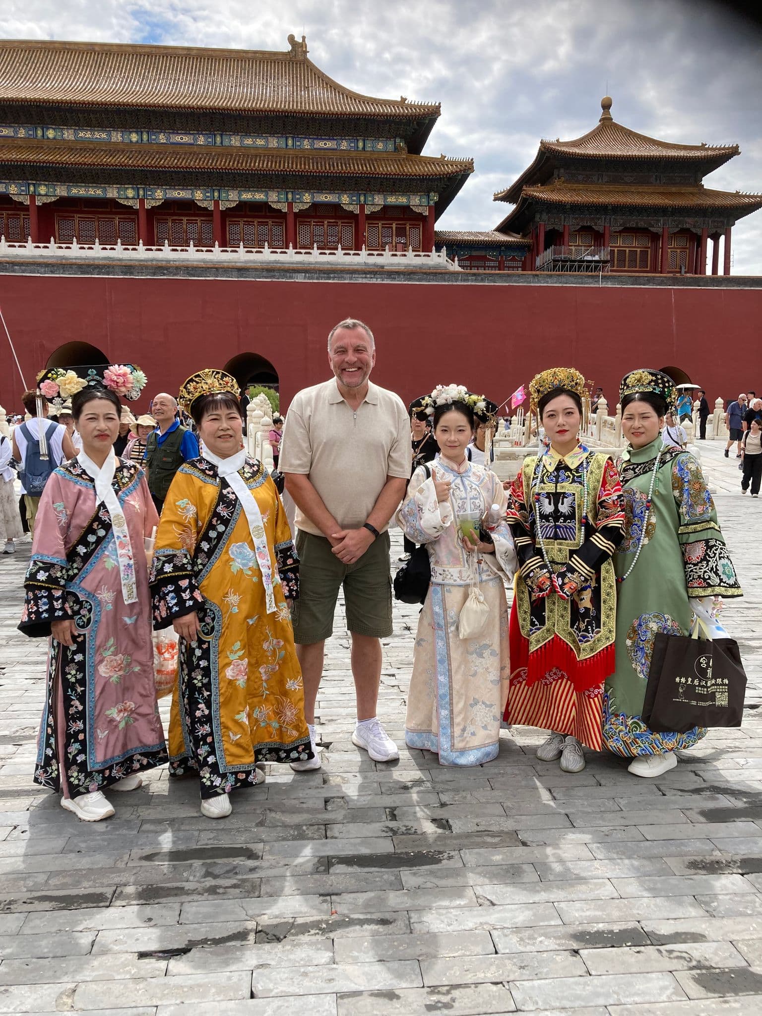 Forbidden City (Palace Museum) entrance in Beijing, China, with a tourist posing alongside women in traditional Qing-era costumes.