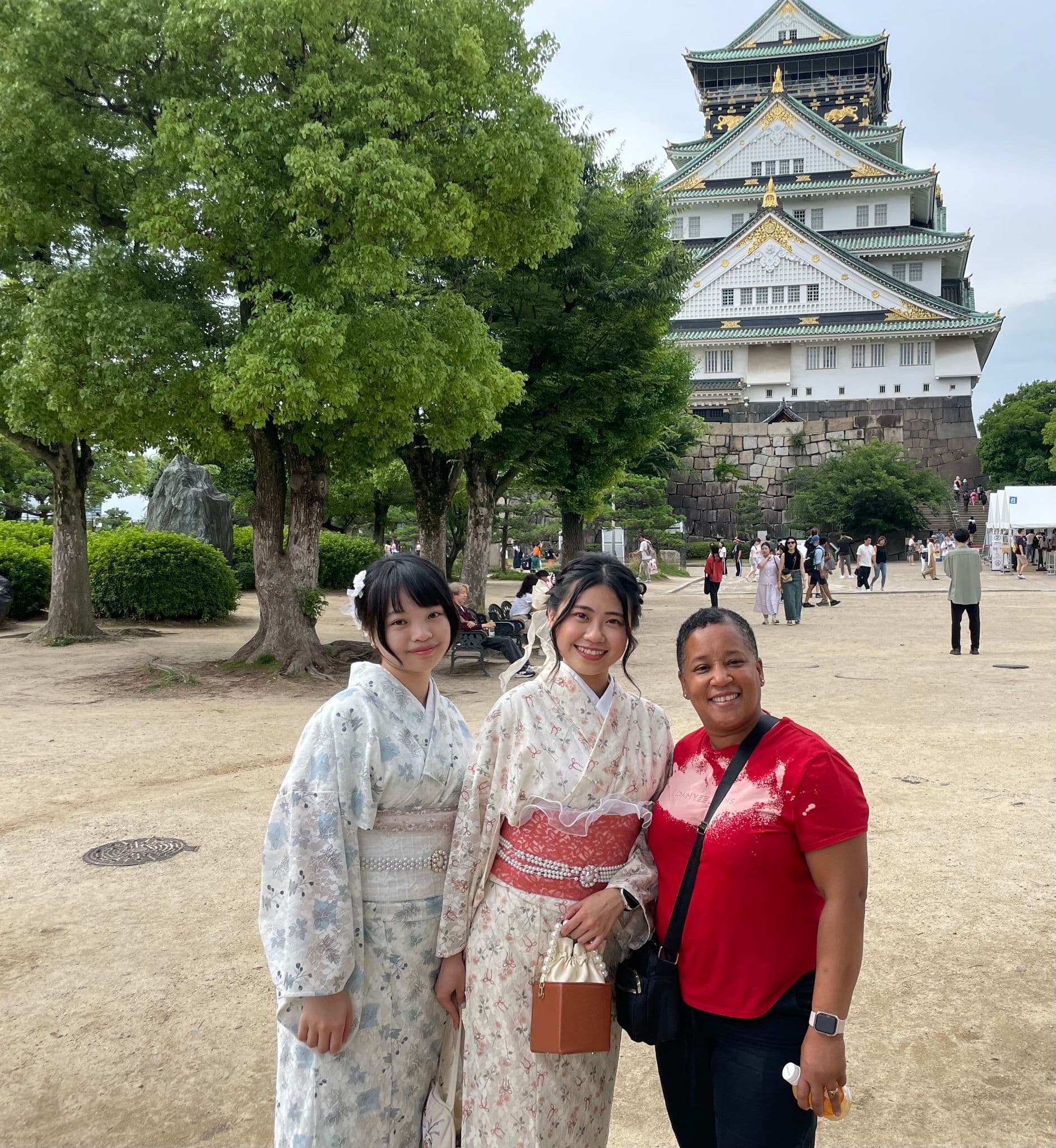 Osaka Castle with three visitors posing together in the park on a trip in Osaka, Japan.
