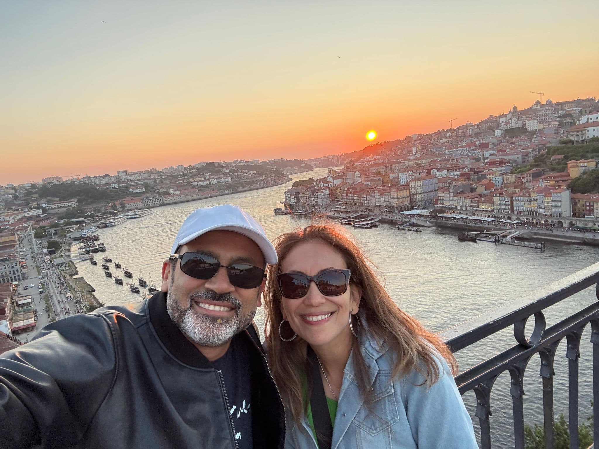Douro River sunset over Porto's Ribeira with two people taking a selfie on the Dom Luís I Bridge, Portugal.