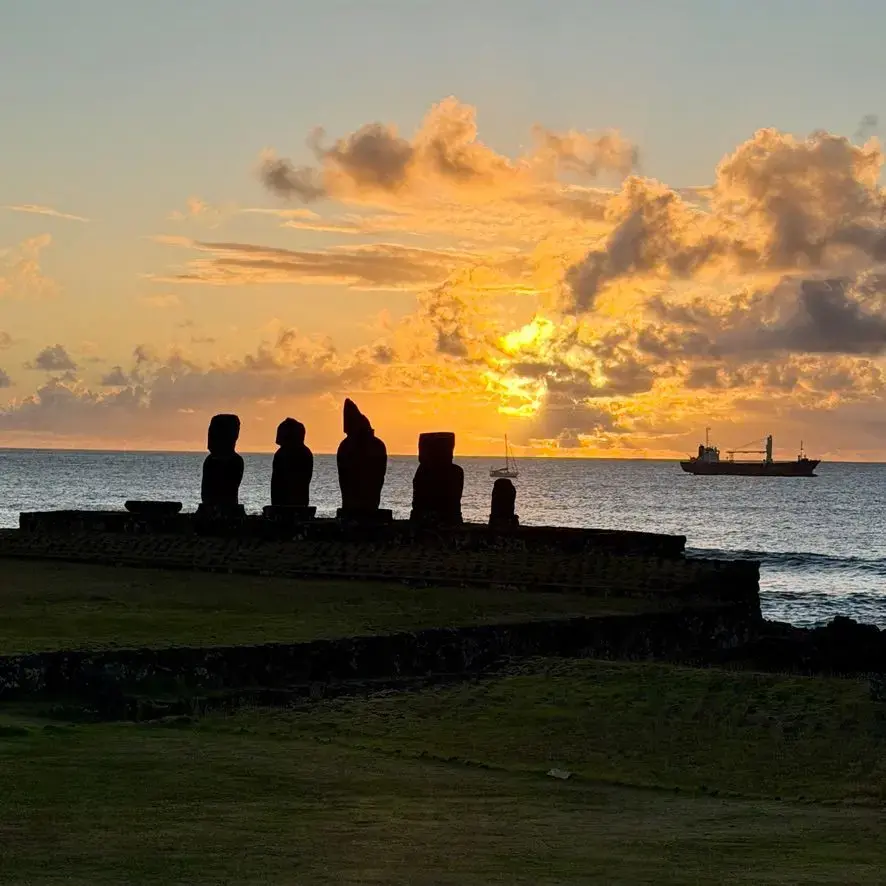 Moai statues silhouetted on the shoreline at sunset at Ahu Tahai, Easter Island, Chile.