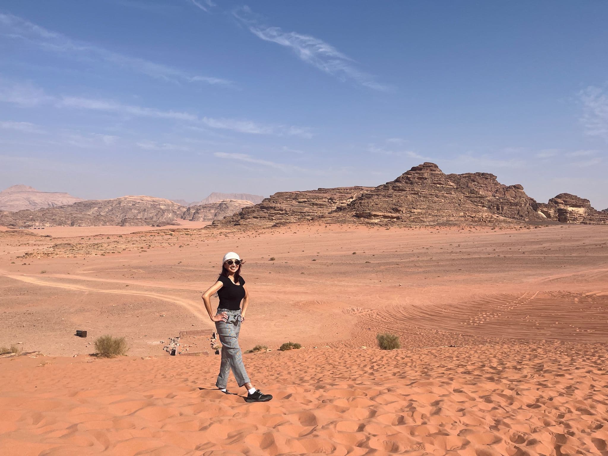 Wadi Rum desert sandstone ridges with a woman standing on red sand dunes in southern Jordan.
