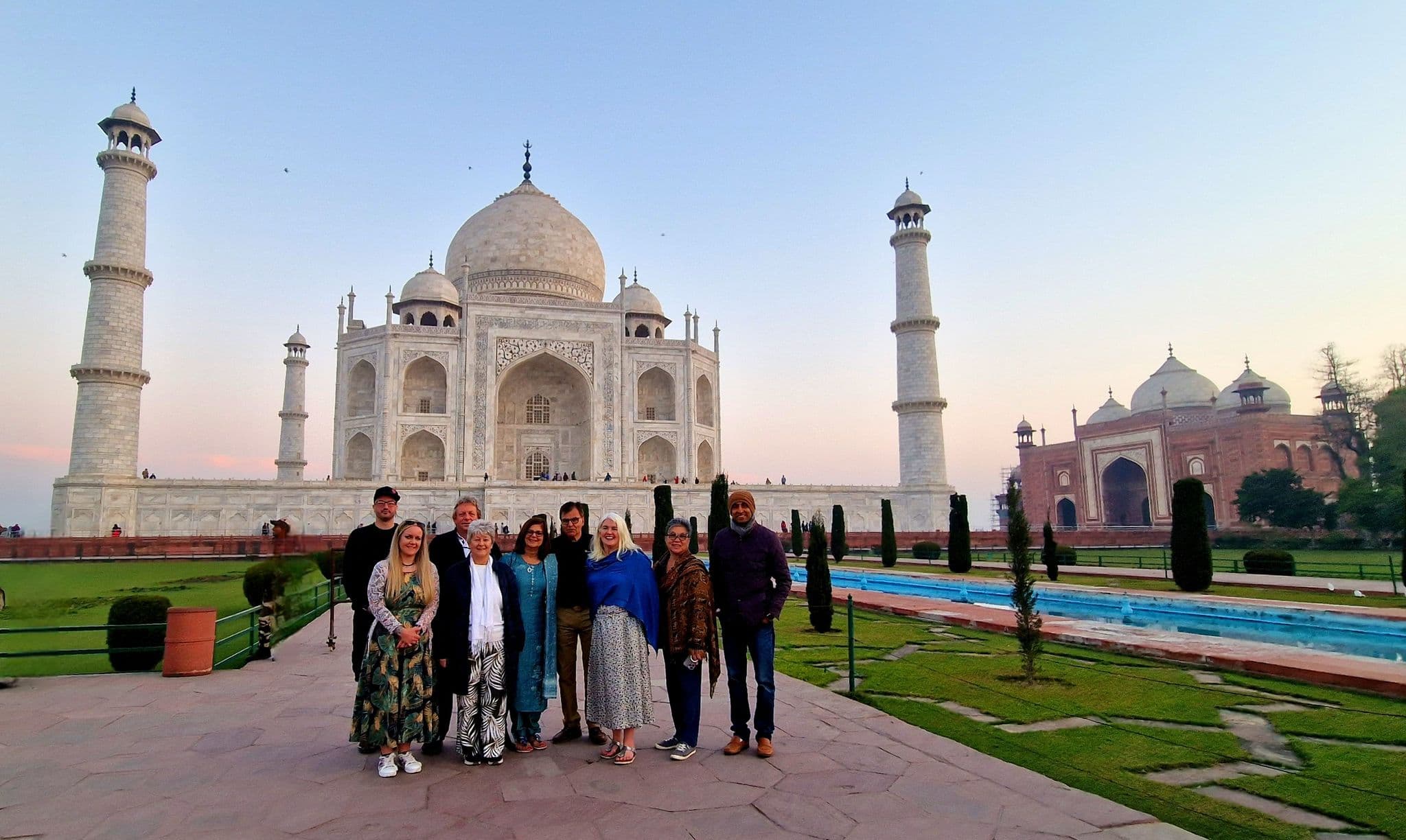 Taj Mahal in Agra, India with a small group of travelers posing on the monument's forecourt.
