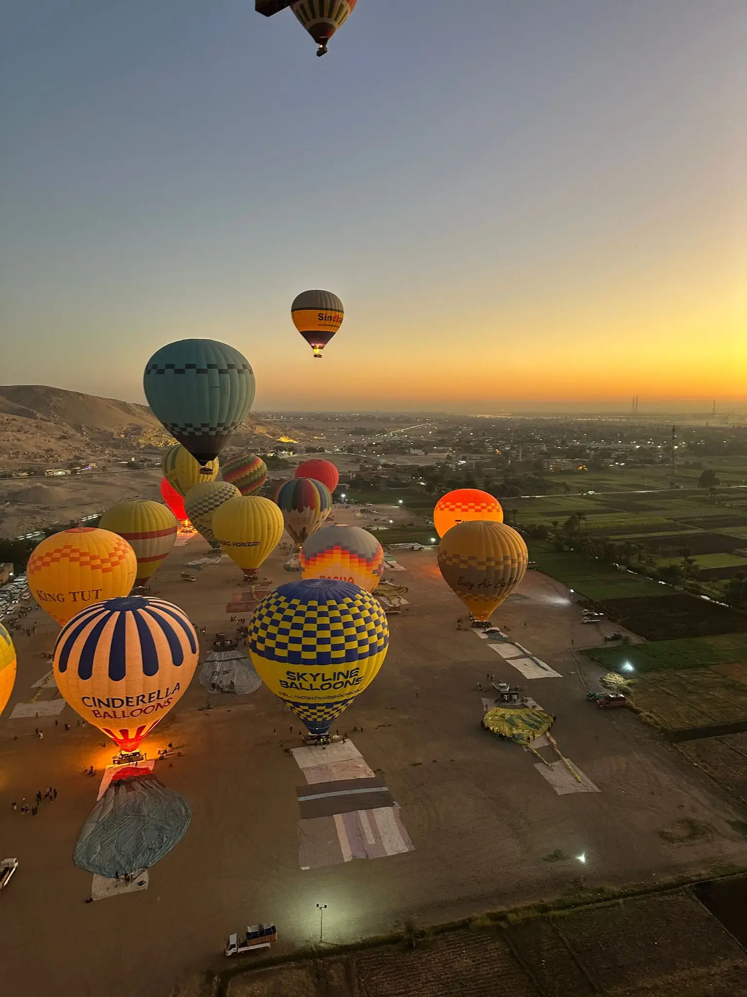 Hot air balloons rising over the Valley of the Kings near Luxor, Egypt at sunrise as crews prepare for a tour.