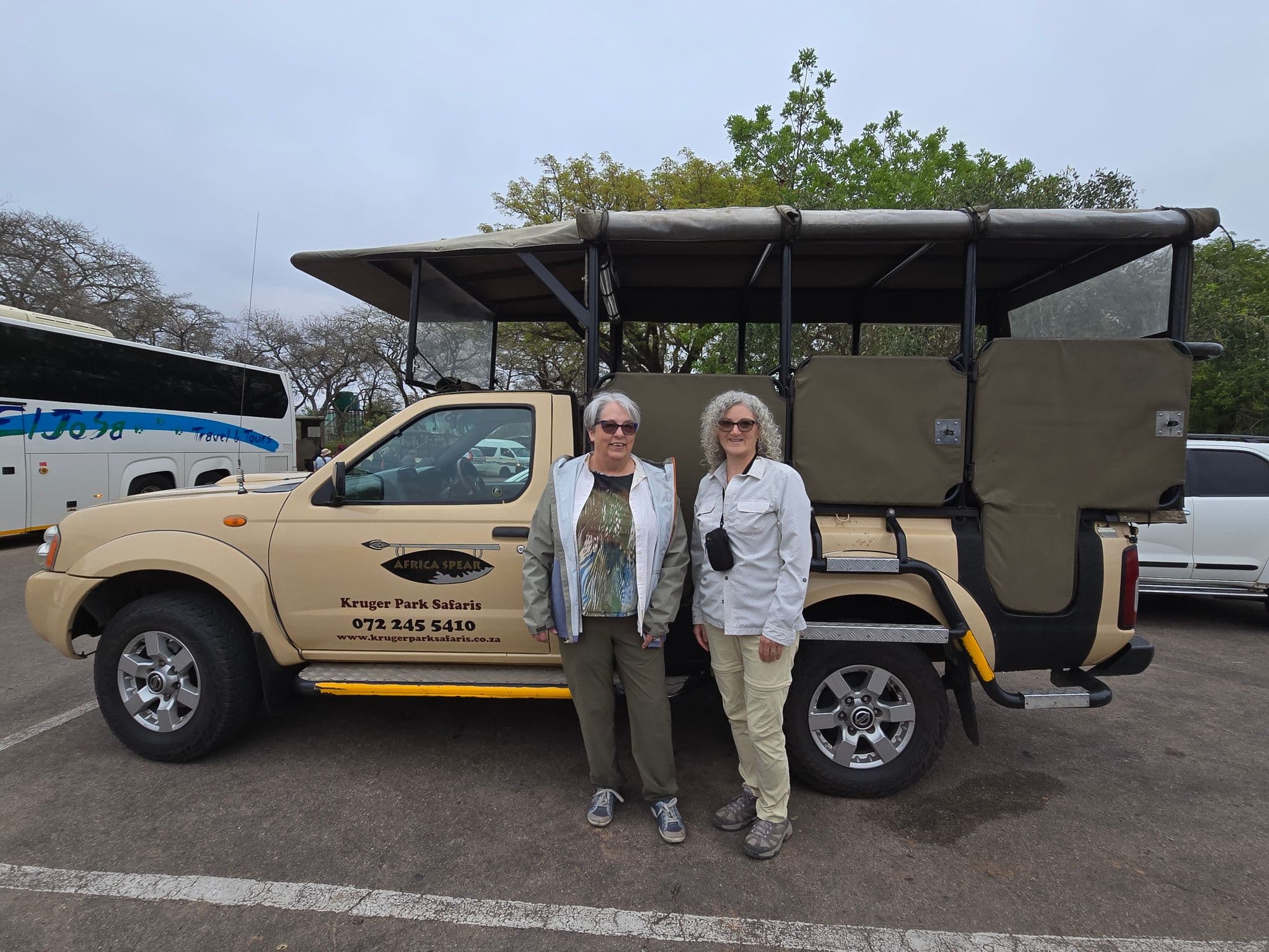 Kruger Park safari vehicle with two travelers standing beside it before a Kruger National Park trip, South Africa