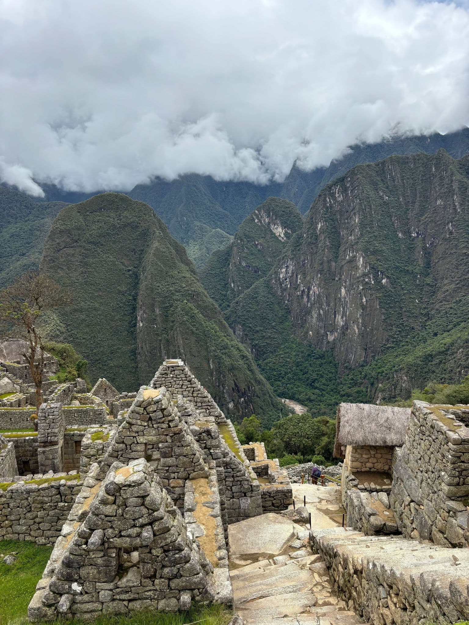 Machu Picchu stone ruins and terraces overlooking steep Andes peaks and low clouds, Cusco Region, Peru.