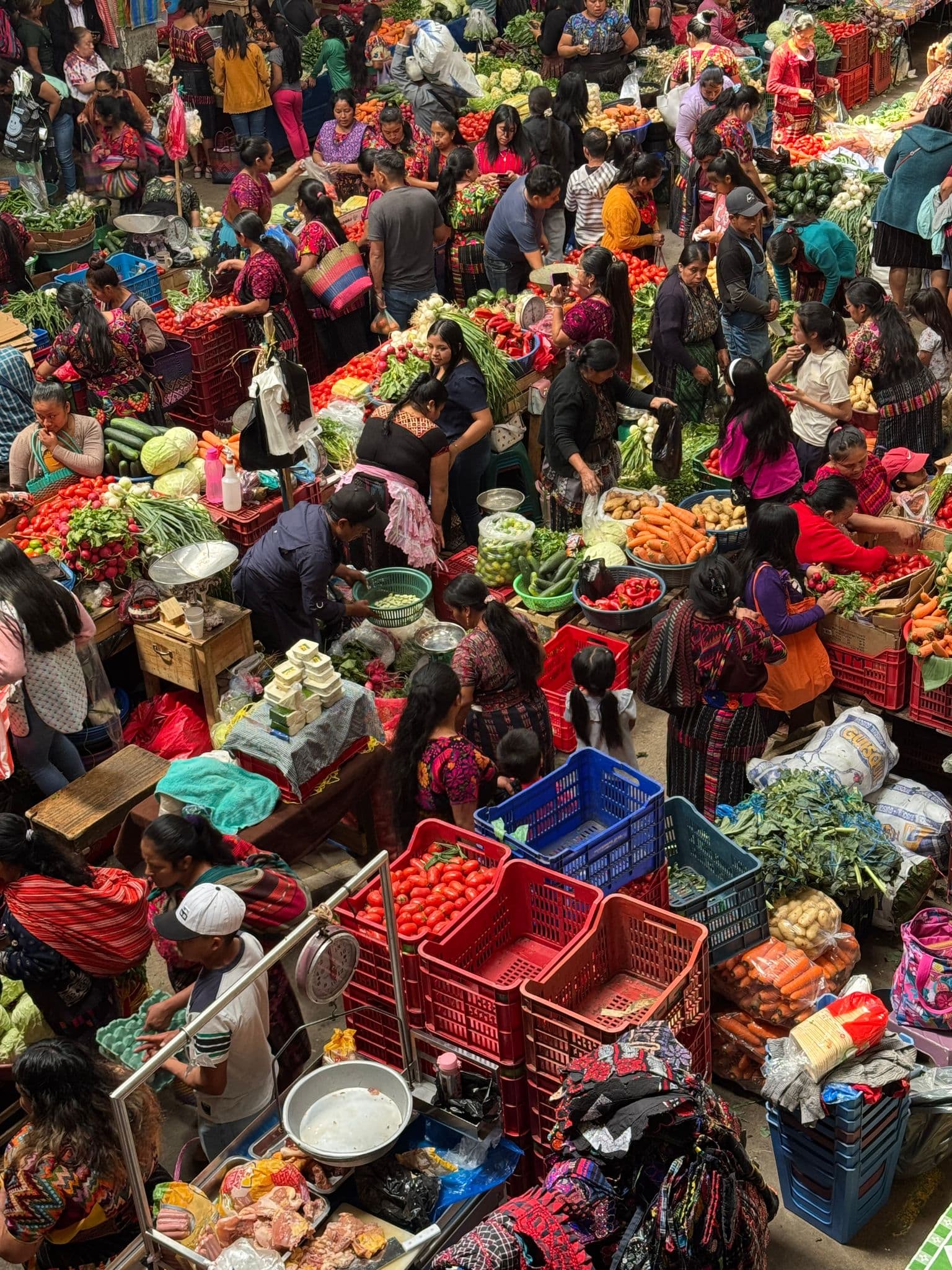 Chichicastenango Market stalls filled with colorful produce and vendors serving shoppers in Chichicastenango, Guatemala.