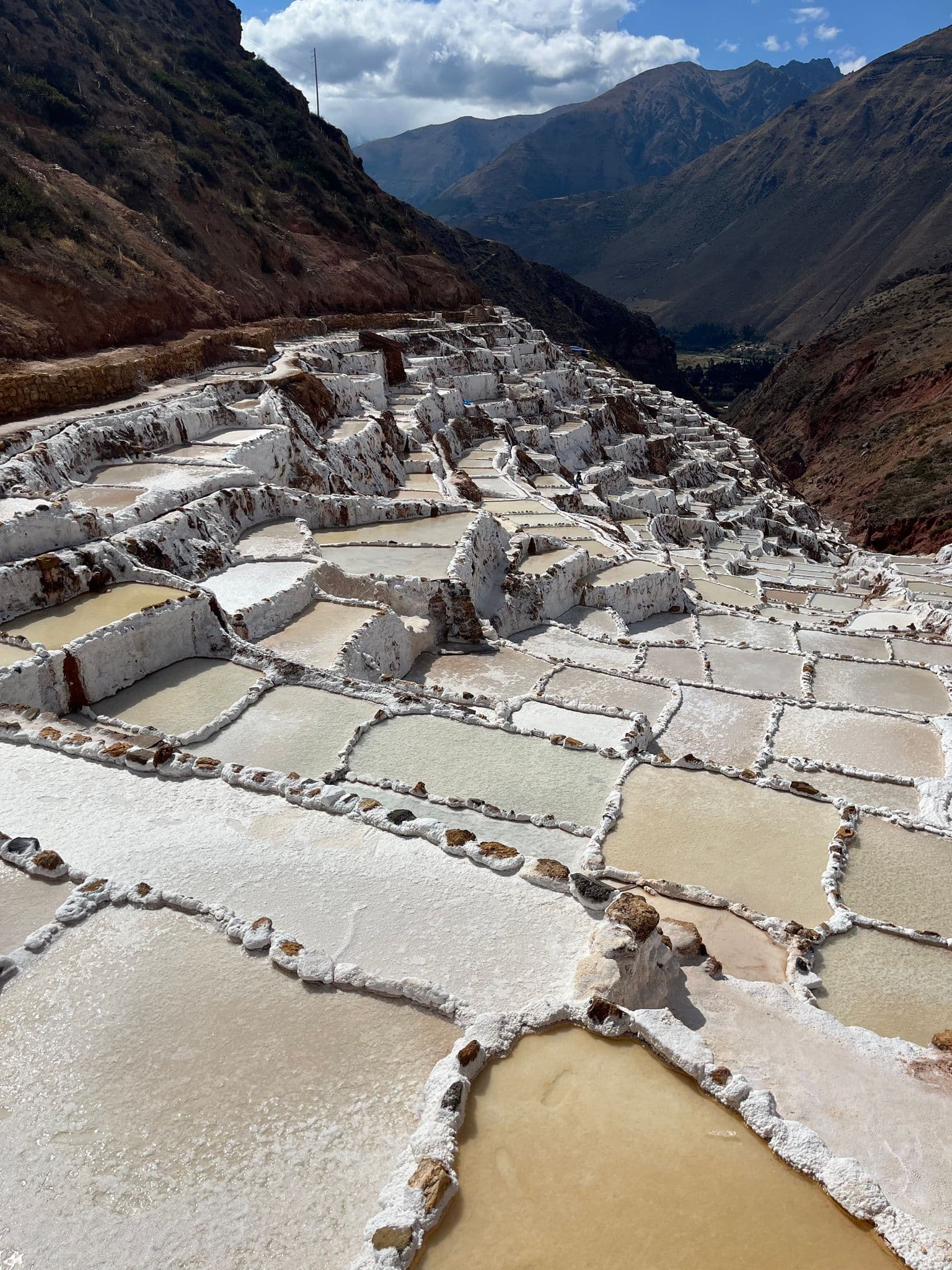 Terraced salt pans at Salinas de Maras in the Sacred Valley, Peru, showing stepped evaporation pools on a mountainside.