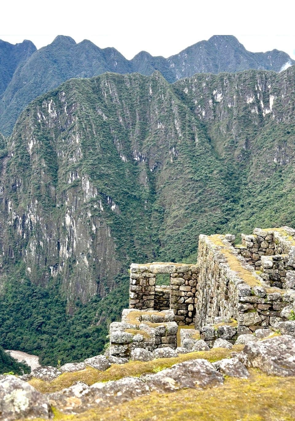 Machu Picchu stone ruins overlooking steep green Andes mountains, Cusco Region, Peru.