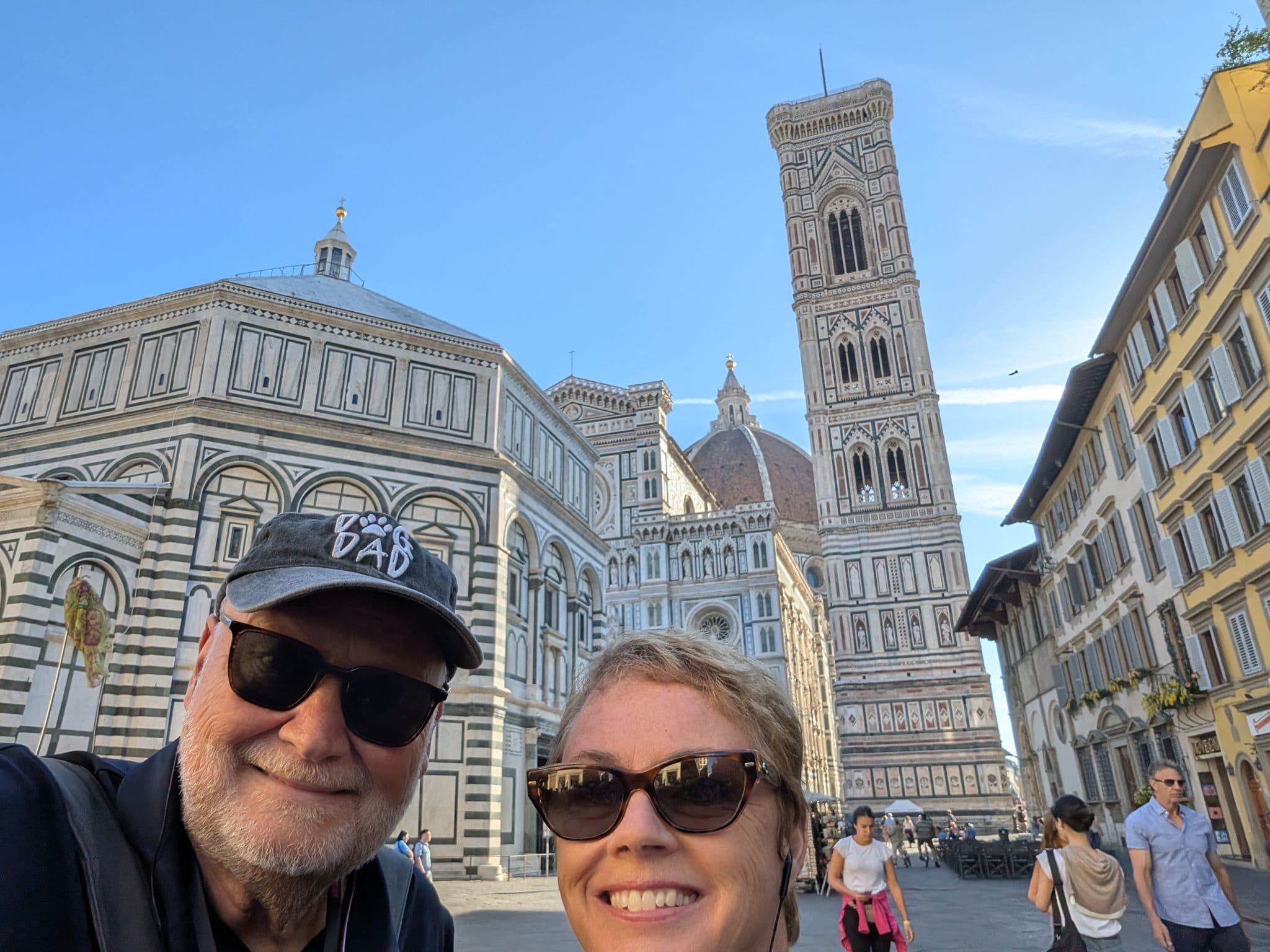 Florence Cathedral (Duomo) and Giotto's Campanile with two travelers taking a selfie in Piazza del Duomo, Florence, Italy.