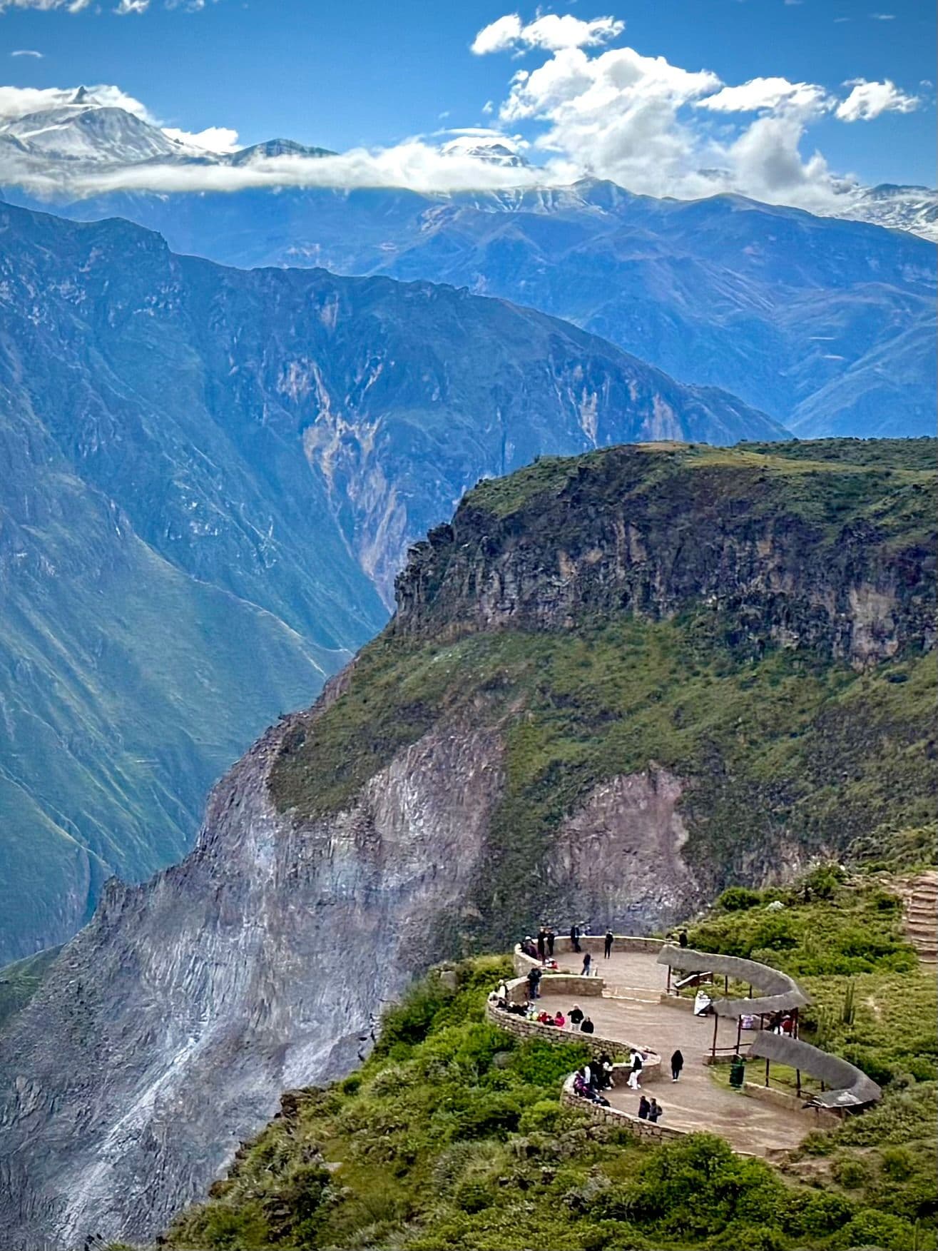 Cruz del Condor viewpoint at Colca Canyon with people on a curved viewing platform overlooking steep canyon cliffs, Arequipa region, Peru.