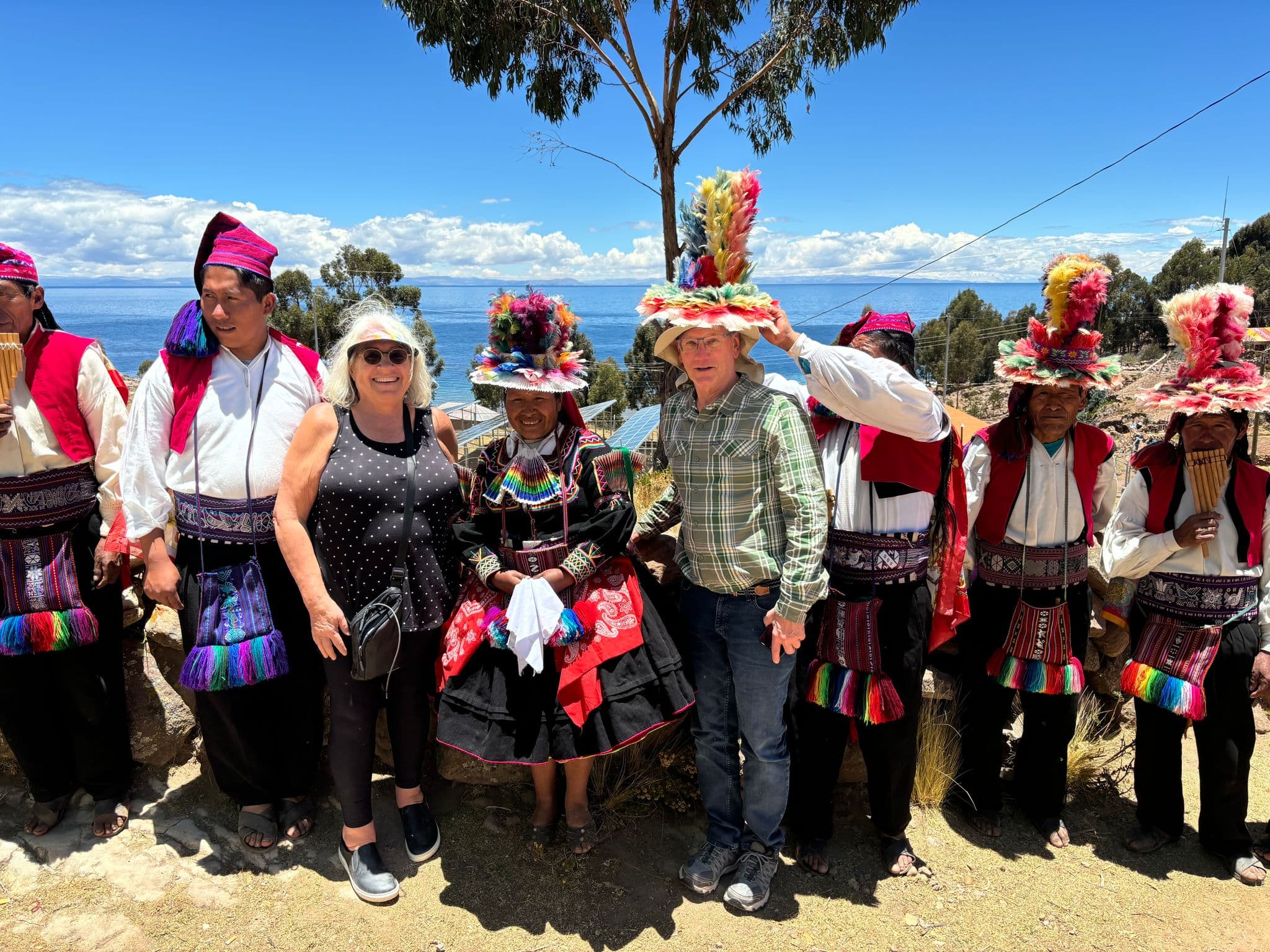 Lake Titicaca with local musicians and two tourists posing on the shore in colorful traditional dress.