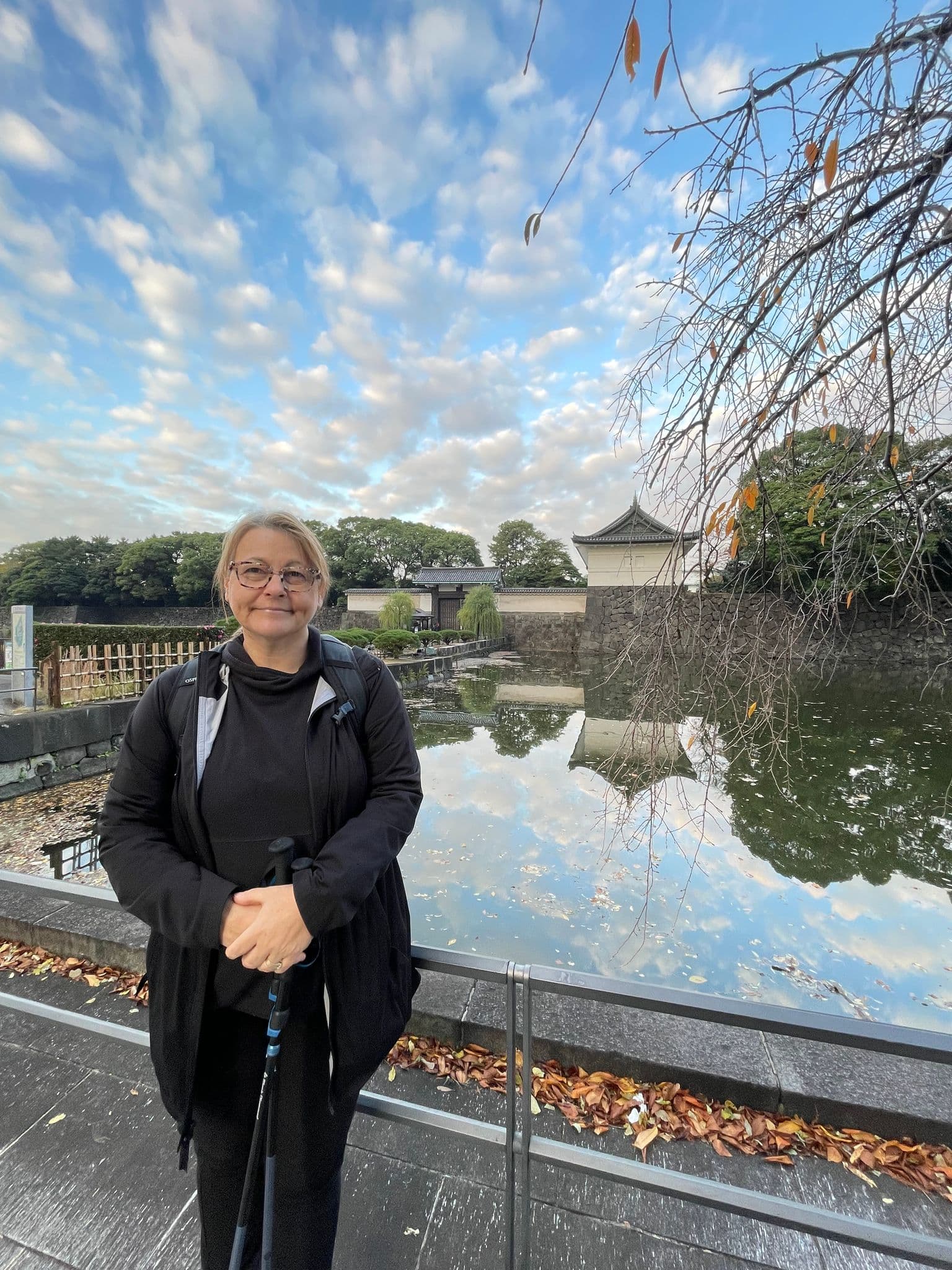 Tokyo Imperial Palace moat and stone walls reflected in water, a traveler standing at a railing, Tokyo, Japan.