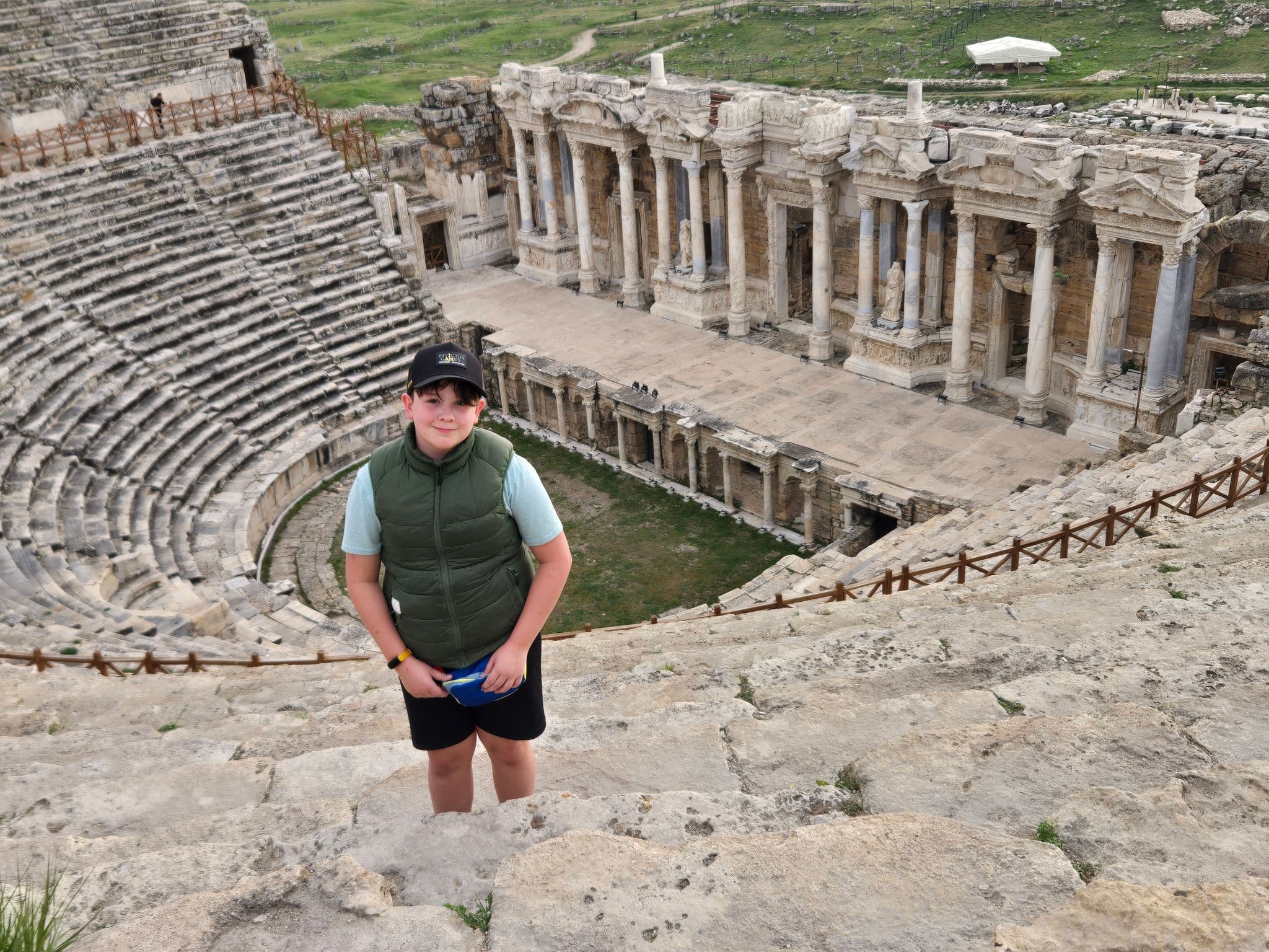 Ancient theatre of Hierapolis with a traveler standing on stone steps overlooking the stage and seating in Hierapolis, Turkey.