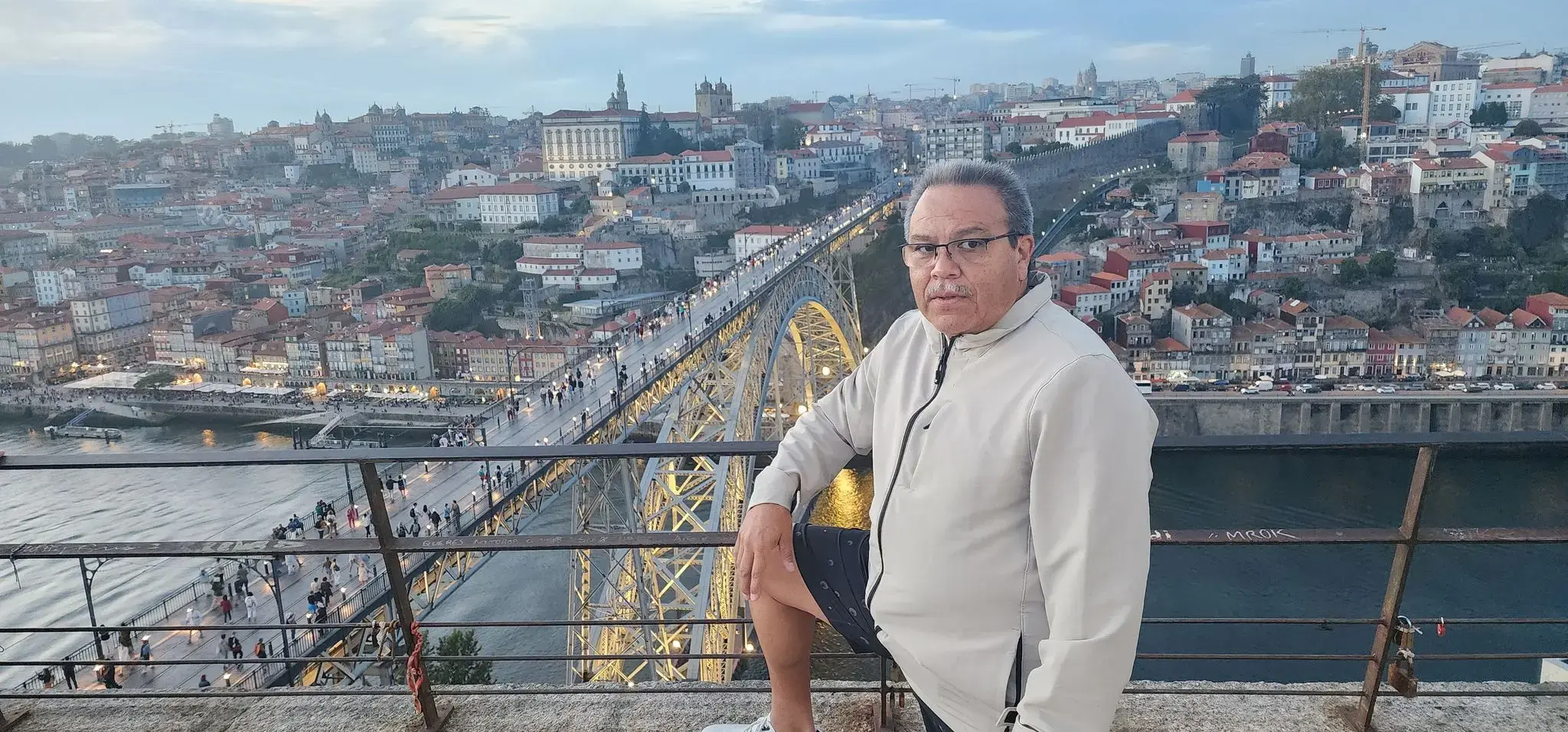 Dom Luís I Bridge over the Douro River with the Porto skyline and a man leaning on a railing, Porto, Portugal.