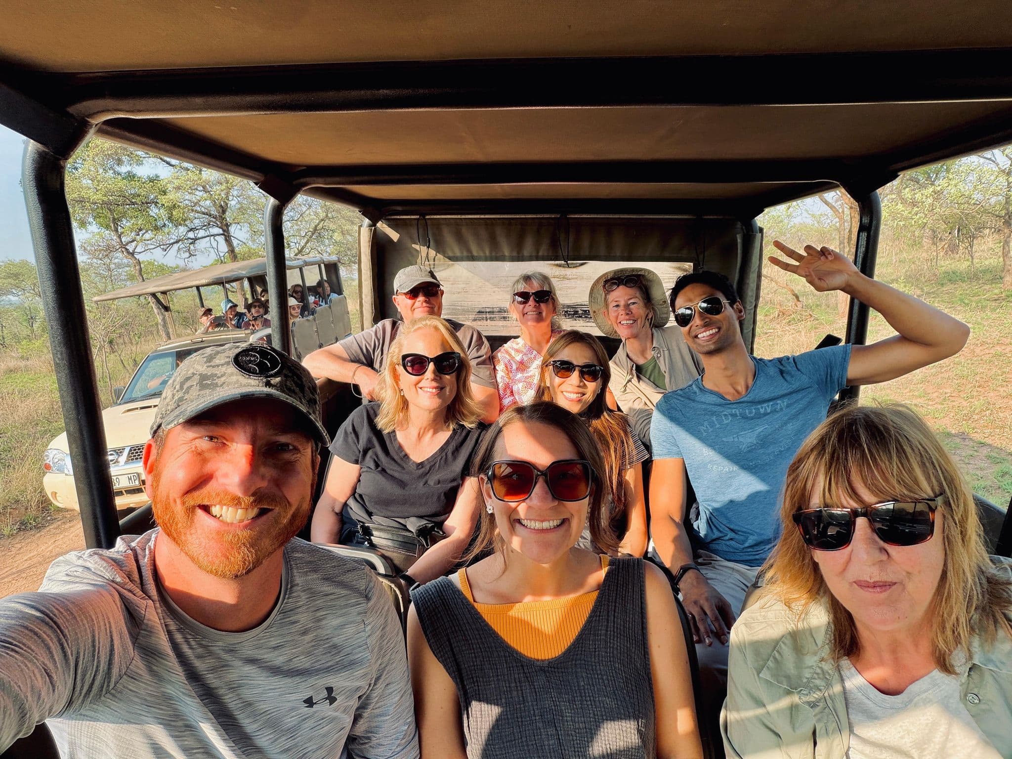 Group of travelers smiling in an open safari vehicle during a trip in Kruger National Park, South Africa.