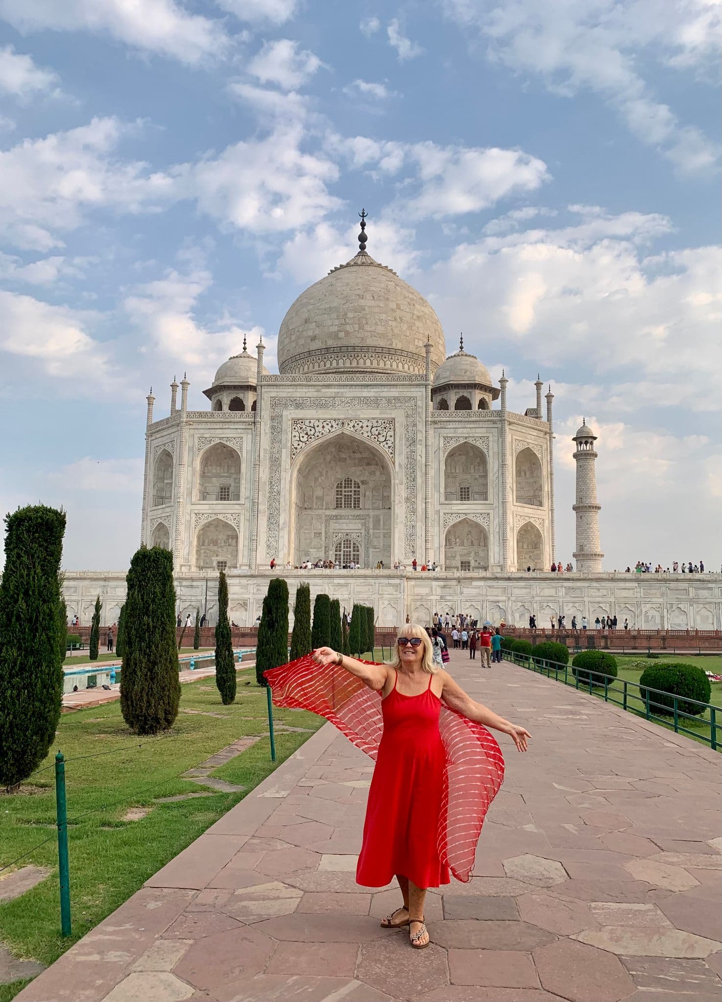 Taj Mahal with a woman in a red dress posing on the pathway in Agra, India