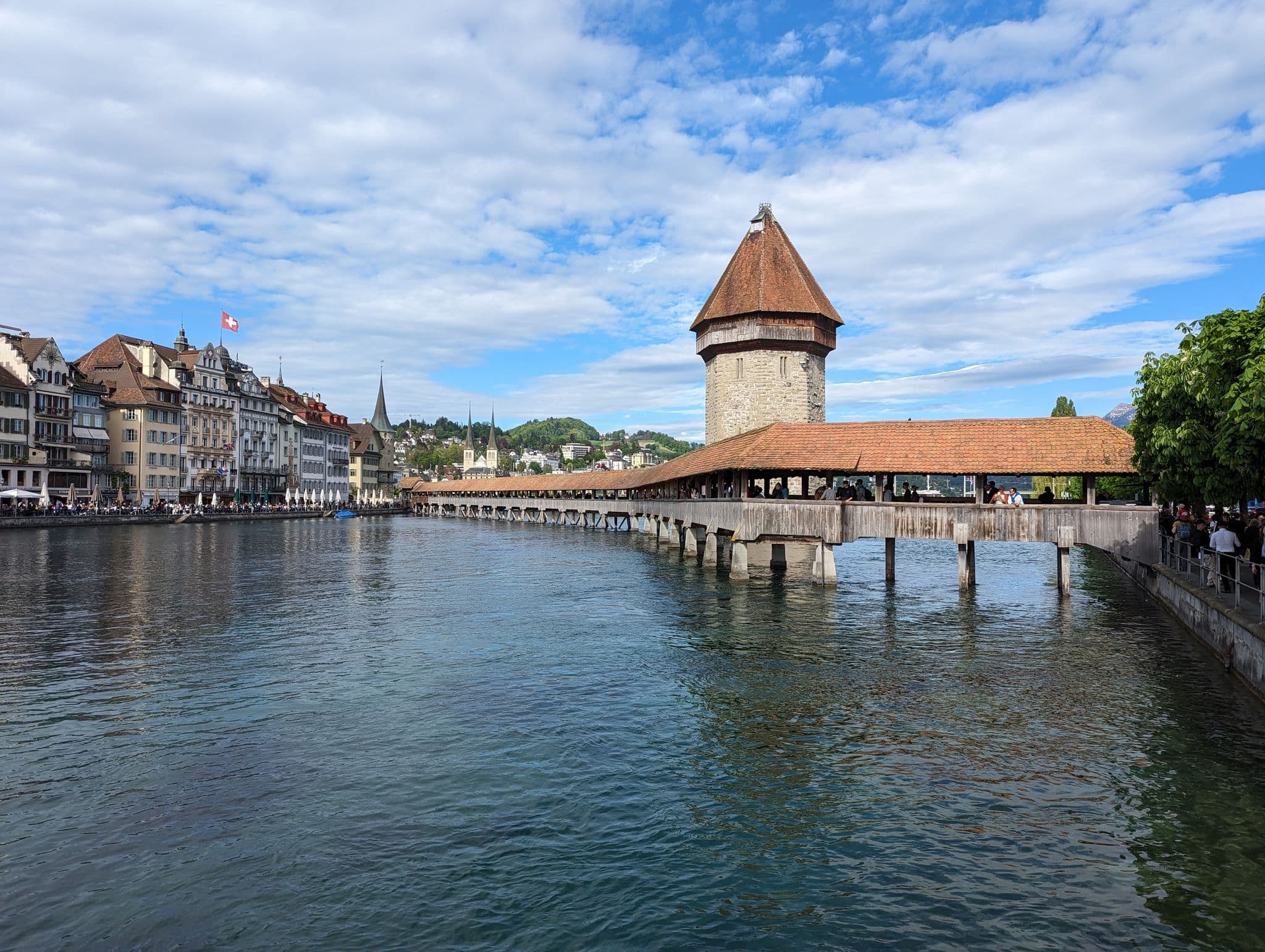 Kapellbrücke (Chapel Bridge) spanning Lake Lucerne with people walking across and the Water Tower in Lucerne, Switzerland.