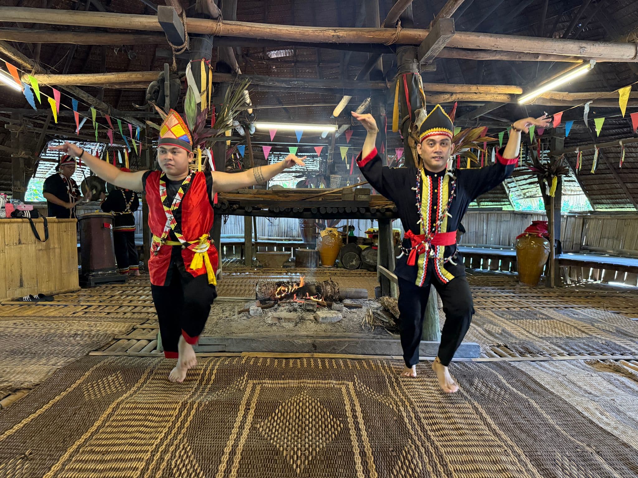 Two performers in traditional Iban dress dancing inside a longhouse at Sarawak Cultural Village, Sarawak, Malaysia.