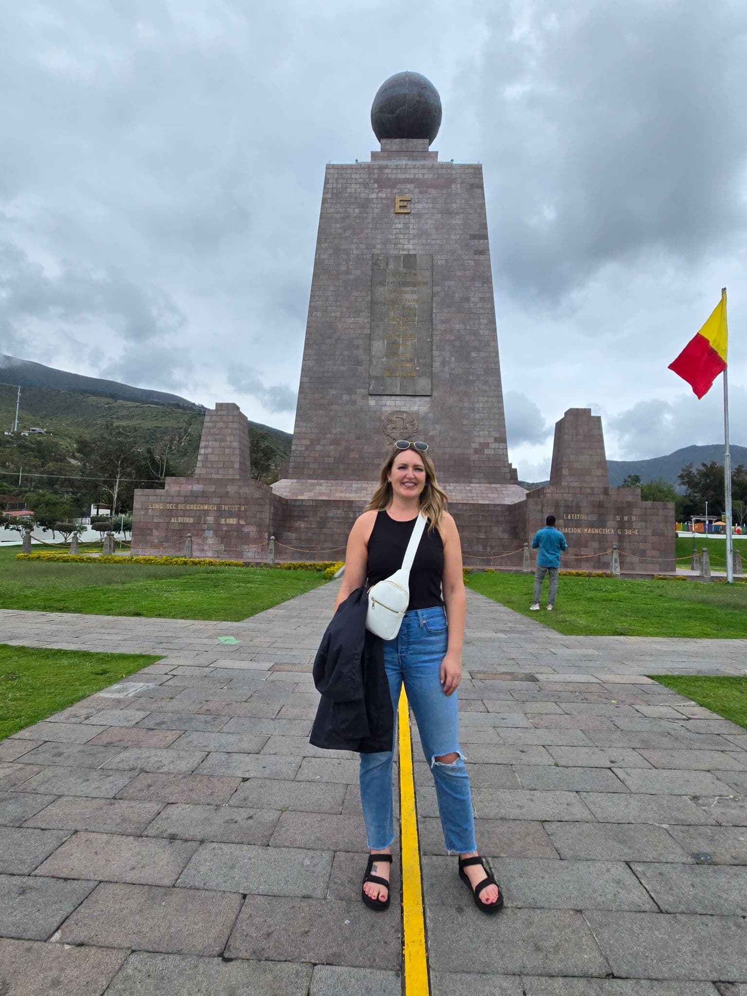 Mitad del Mundo Monument with a person standing on the yellow equator line in Ciudad Mitad del Mundo, near Quito, Ecuador.