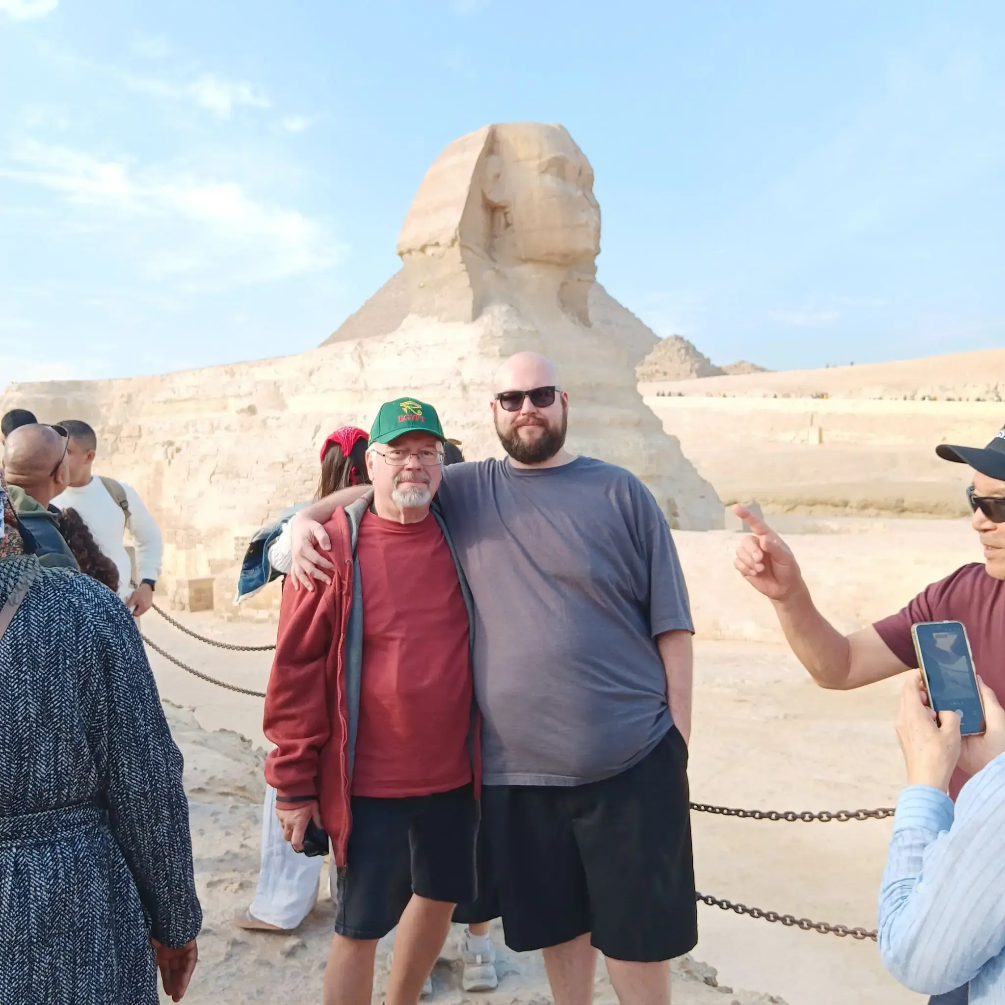 Great Sphinx of Giza with two men posing arm-in-arm near the monument on a tour in Giza, Egypt.