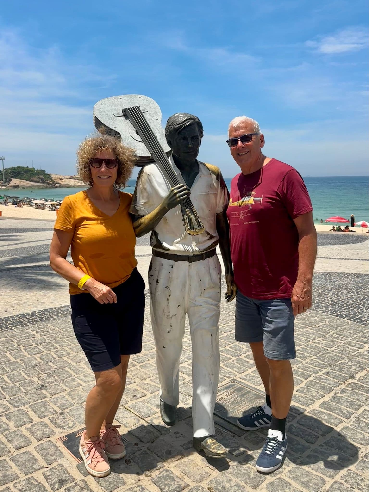Tom Jobim statue with two tourists posing beside it on the promenade at Ipanema Beach, Rio de Janeiro, Brazil.