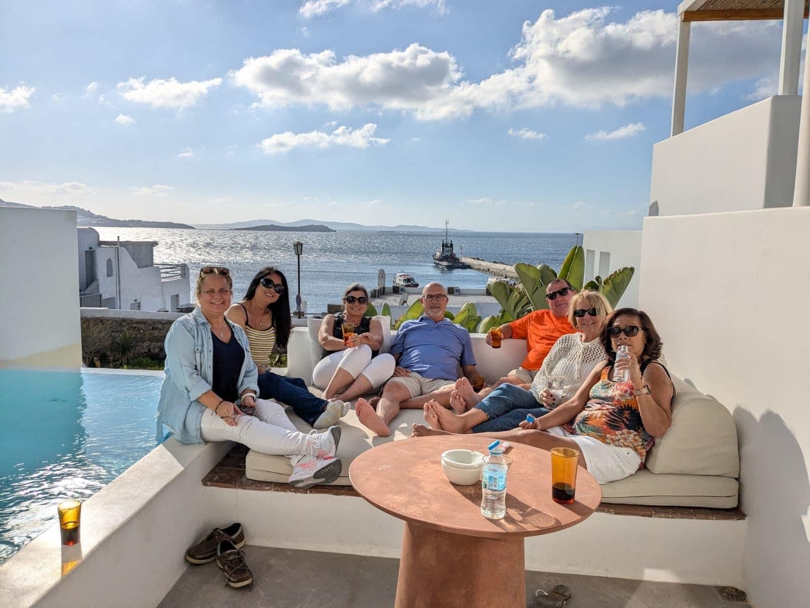 Mykonos waterfront and pier with a group of travelers relaxing on a seaside terrace, Mykonos, Greece.