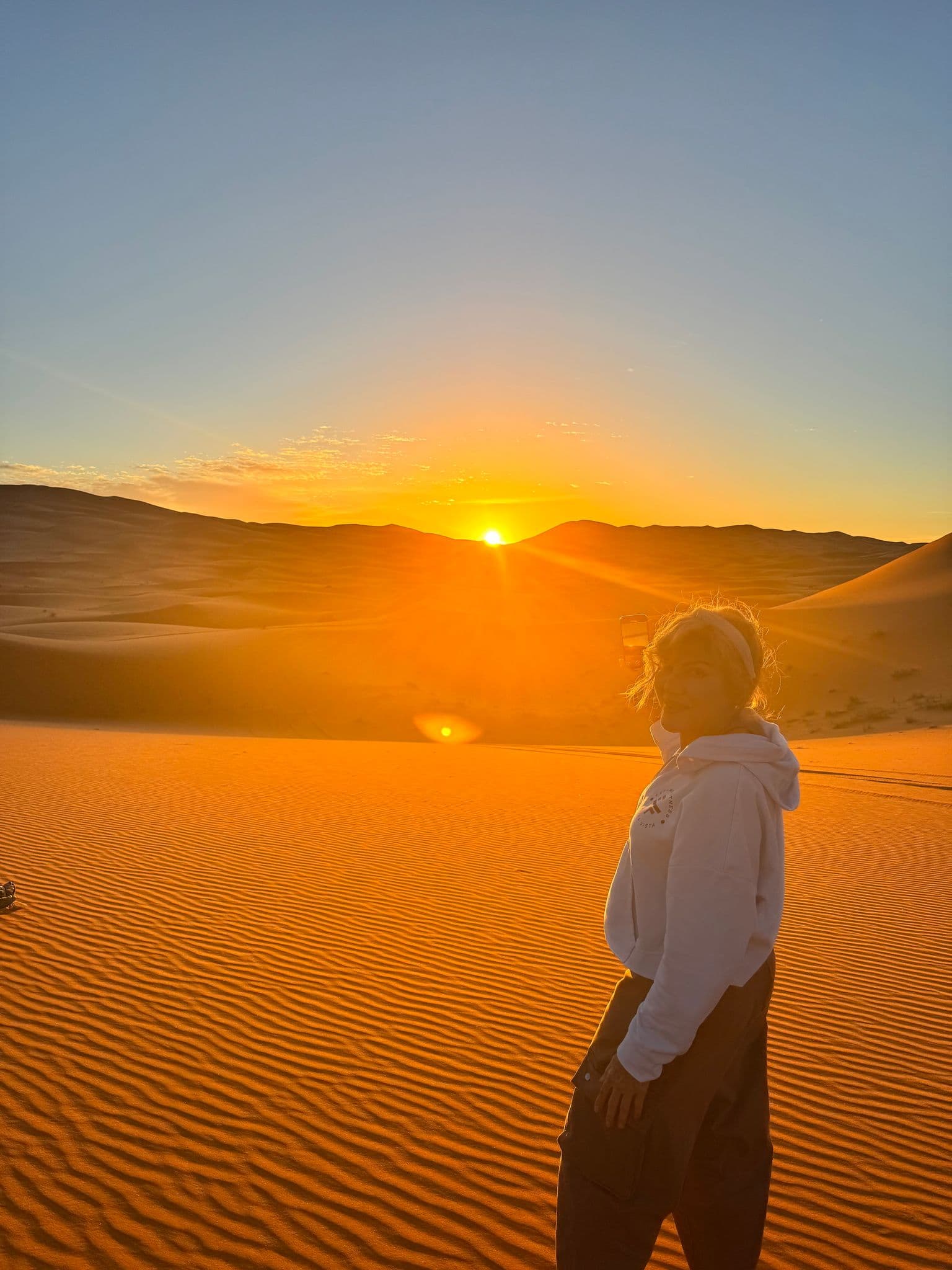 Sahara Desert sand dunes at sunset with a traveler standing in the foreground.