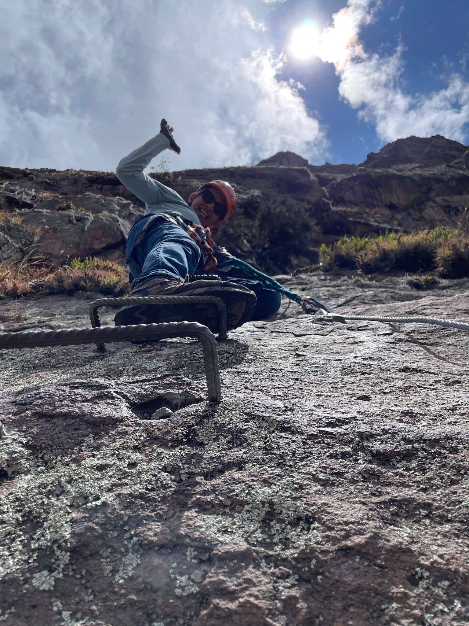 Climber on metal rungs ascending a rocky via ferrata route near Cuzco, Peru.