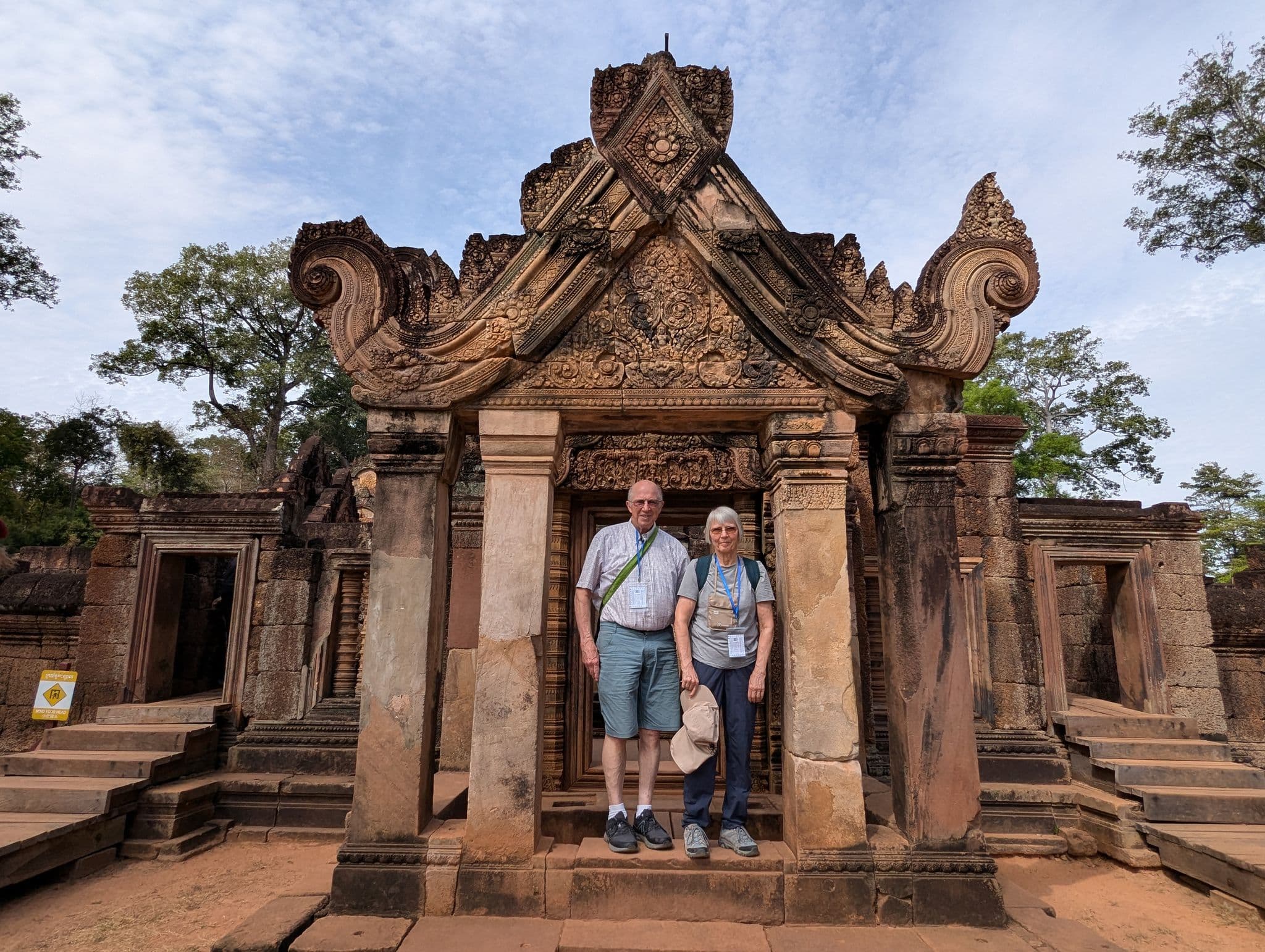 Banteay Srei temple entrance with two travelers standing in the carved doorway, Siem Reap, Cambodia.