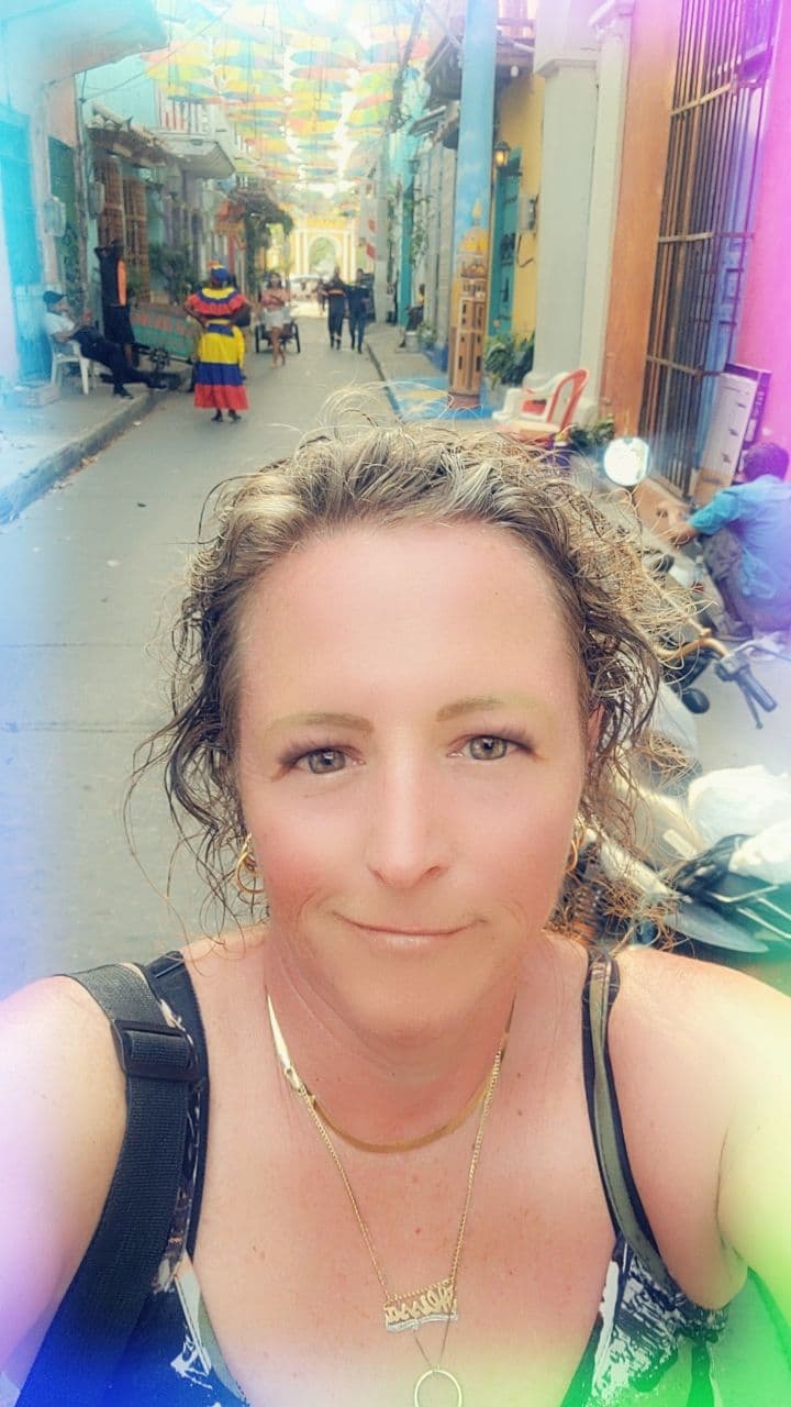 Woman taking a selfie on an umbrella-covered street in Cartagena Old Town, Colombia.