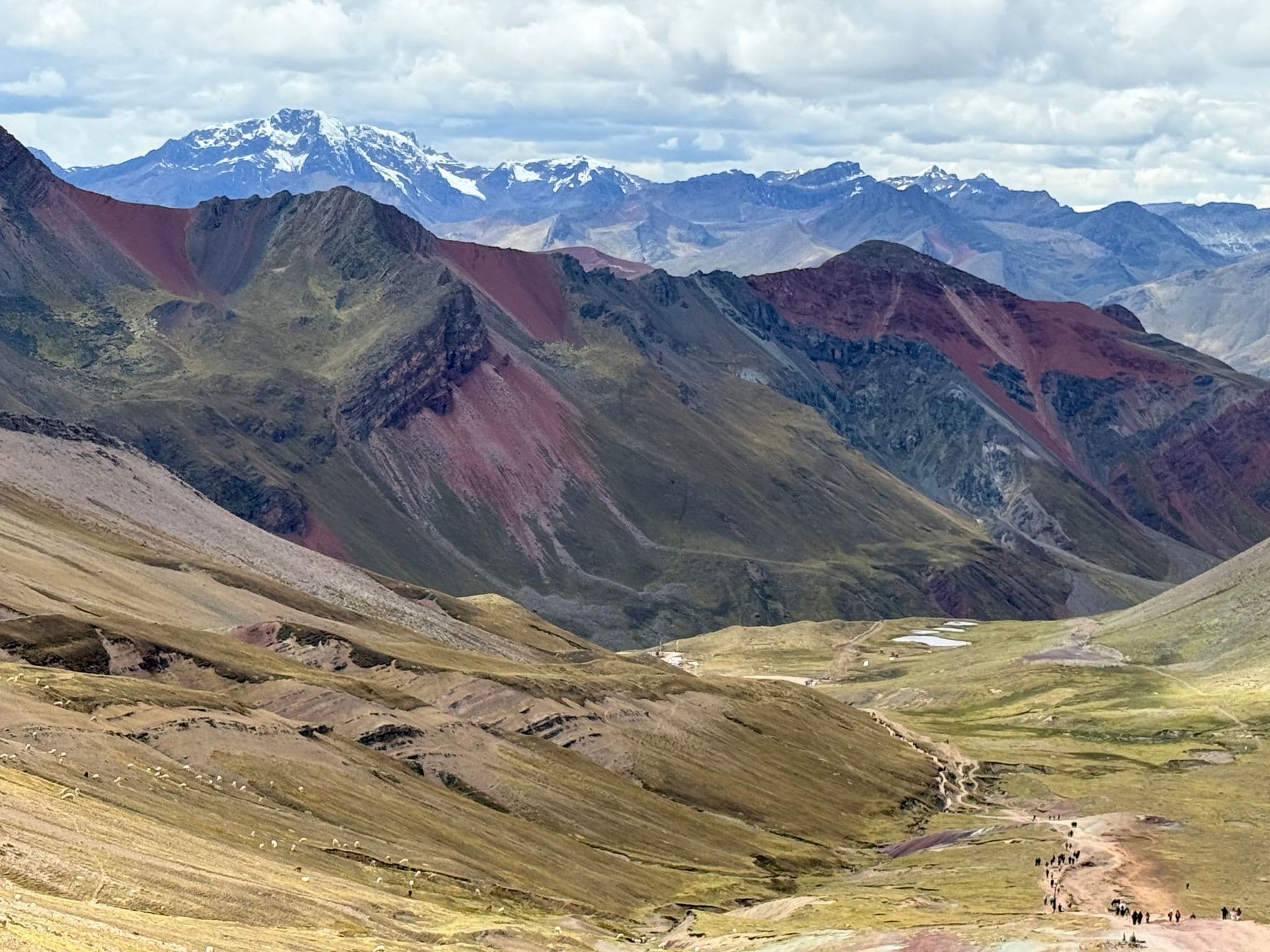 Rainbow Mountain (Vinicunca) and colorful Andes slopes with hikers on a trail during a high-altitude trek near Cusco, Peru.