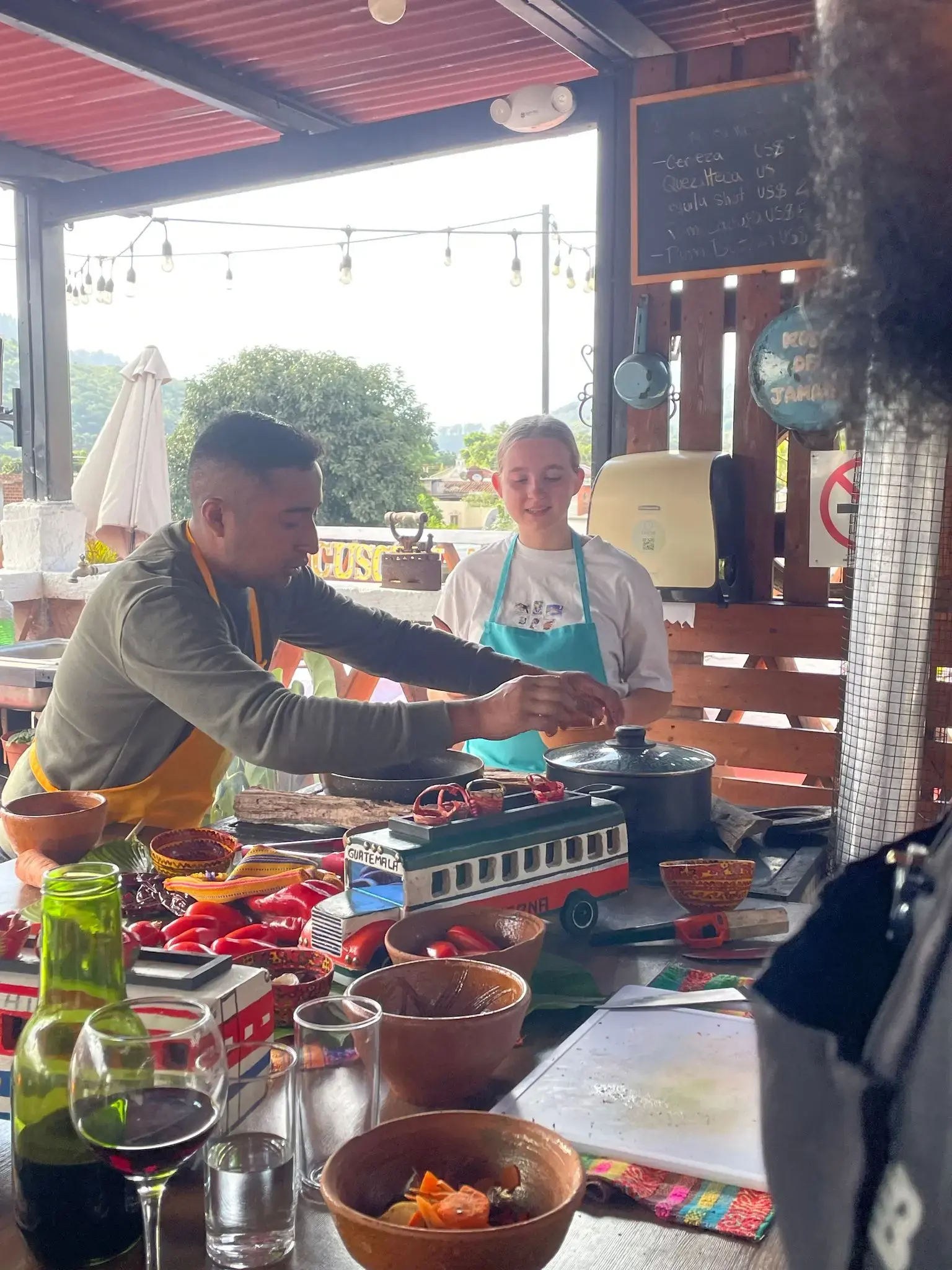 Hands-on cooking class with an instructor and a girl preparing food amid colorful chilies and bowls, Guatemala