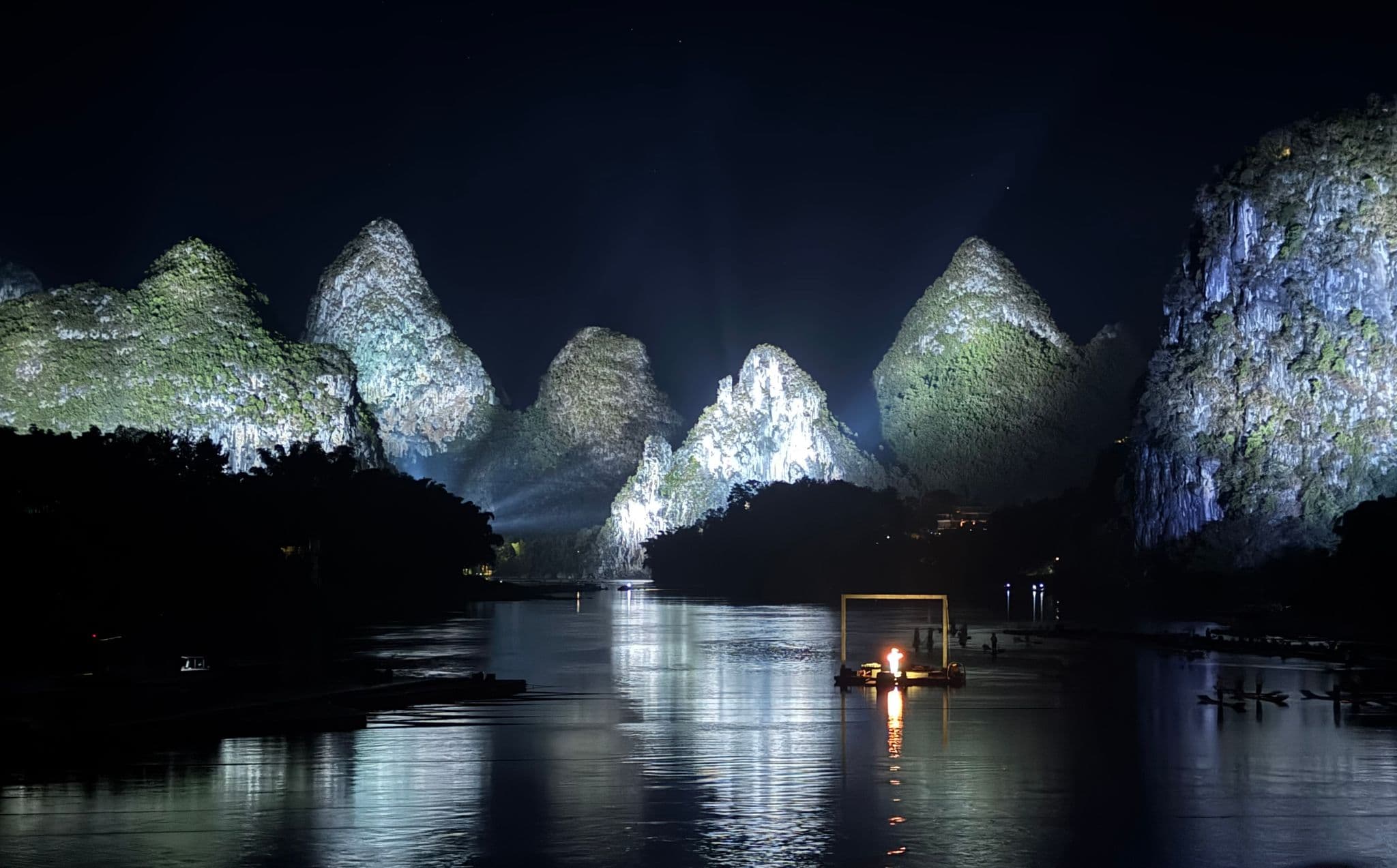 Impression Liu Sanjie floating stage with a small fire on the Li River and illuminated karst mountains in Yangshuo, China.