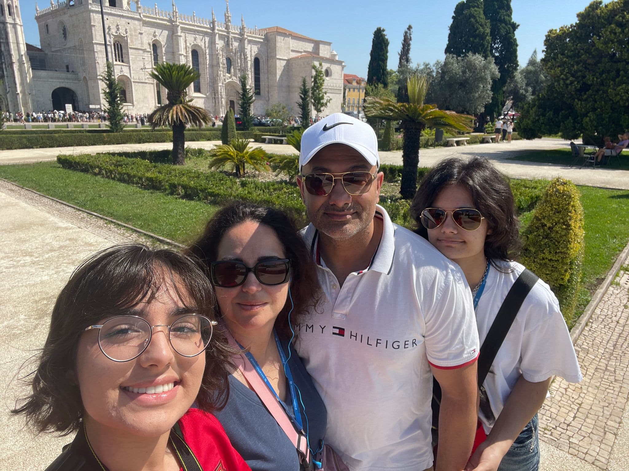 Jerónimos Monastery in Belém, Lisbon, Portugal with four travelers posing for a selfie on the monastery grounds.