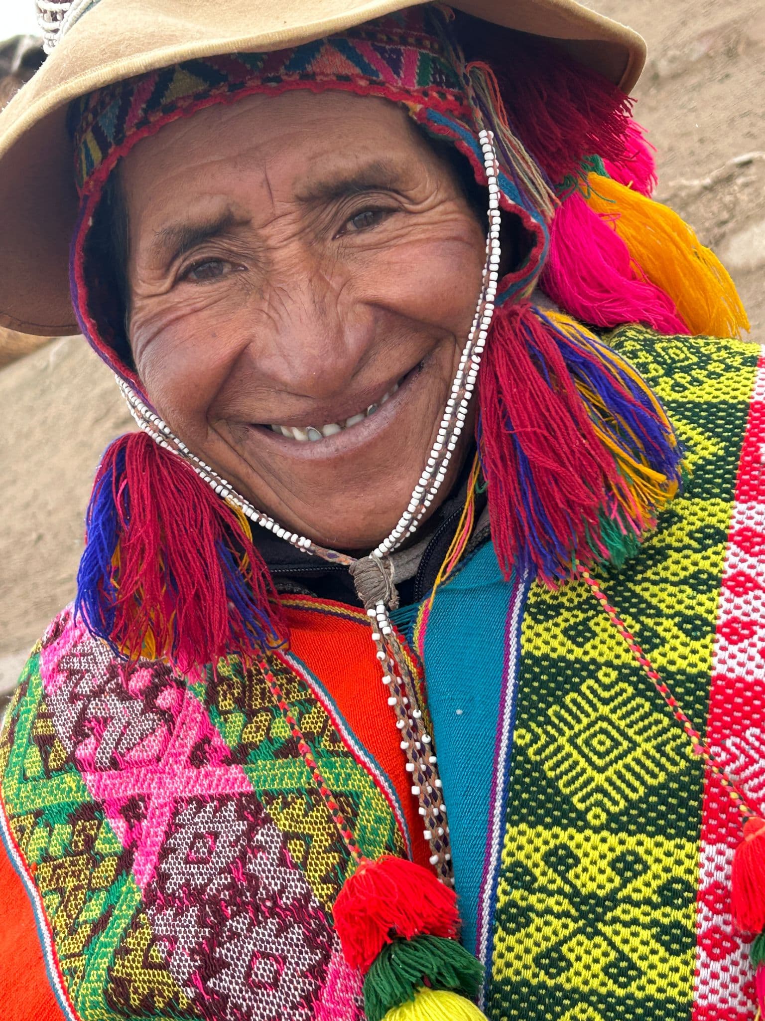 Smiling man wearing bright traditional Andean textiles and a hat, portrait near Vinicunca (Rainbow Mountain), Peru.