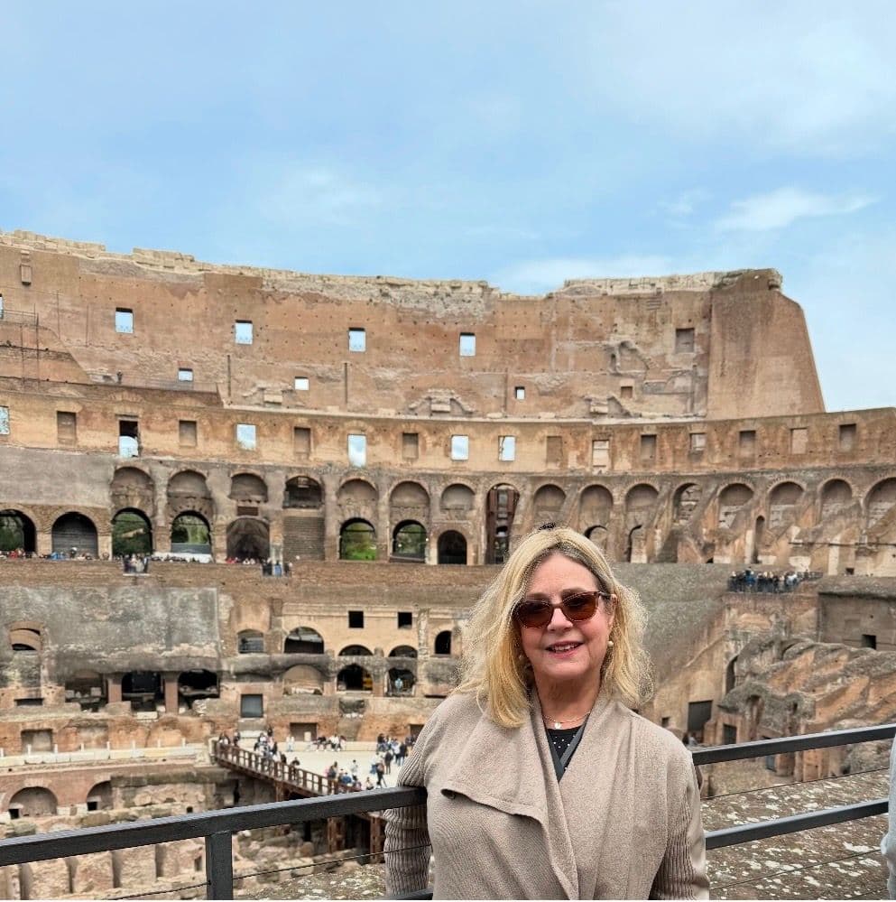 The Colosseum in Rome with a woman leaning on a railing overlooking the arena during a guided tour, Rome, Italy.