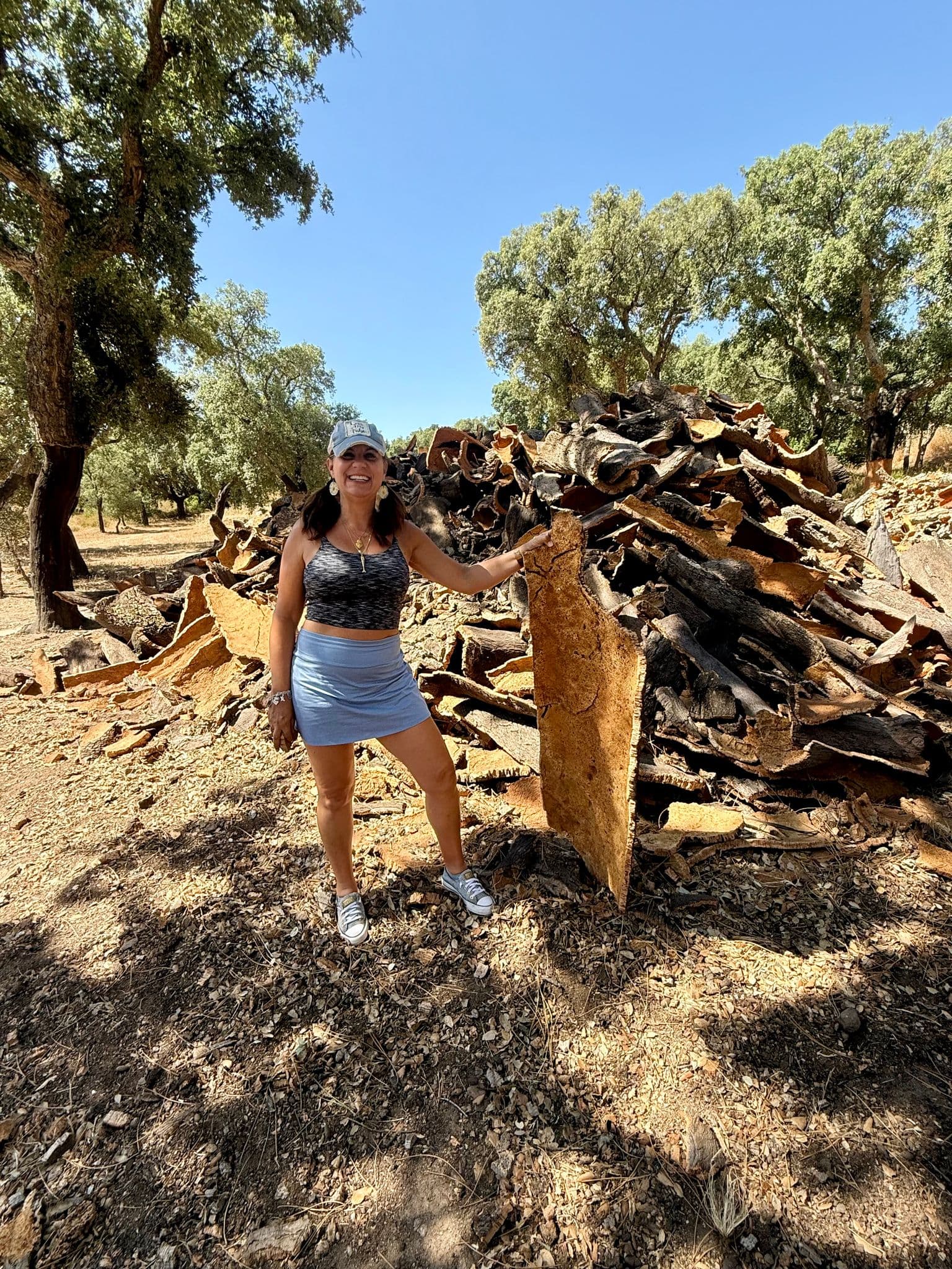 Large stack of harvested cork bark with a woman posing beside it in Monchique, southern Portugal.