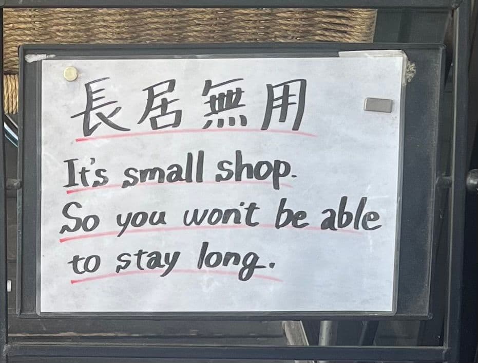 Handwritten café sign reading It's small shop. So you won't be able to stay long outside a small cafe in Nippombashi, Osaka, Japan.